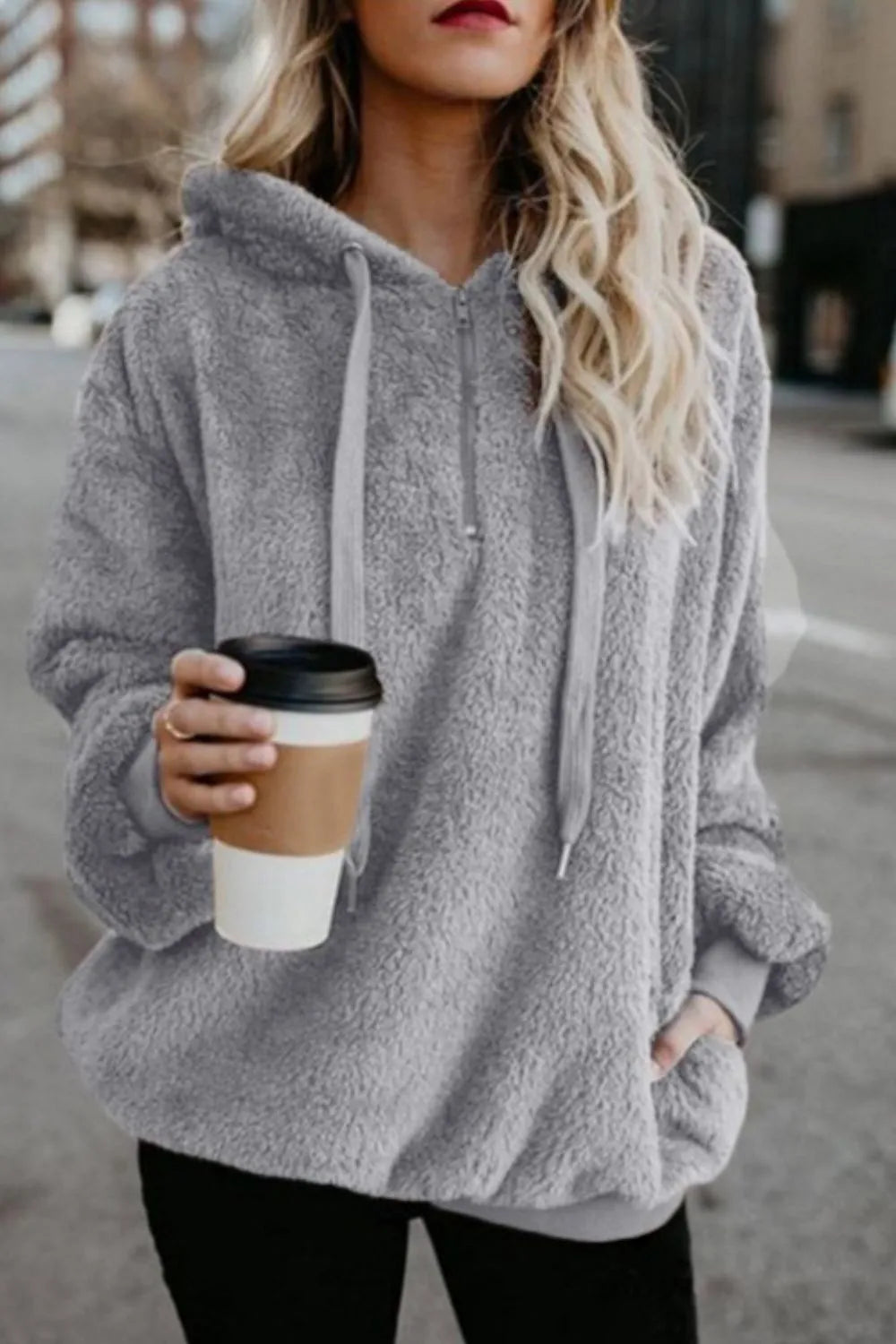Cozy Full Size Teddy Hoodie with Quarter-Zip and Drawstring, Opaque & Slightly Stretchy, 100% Polyester, modeled by a woman holding a coffee cup in a city setting.