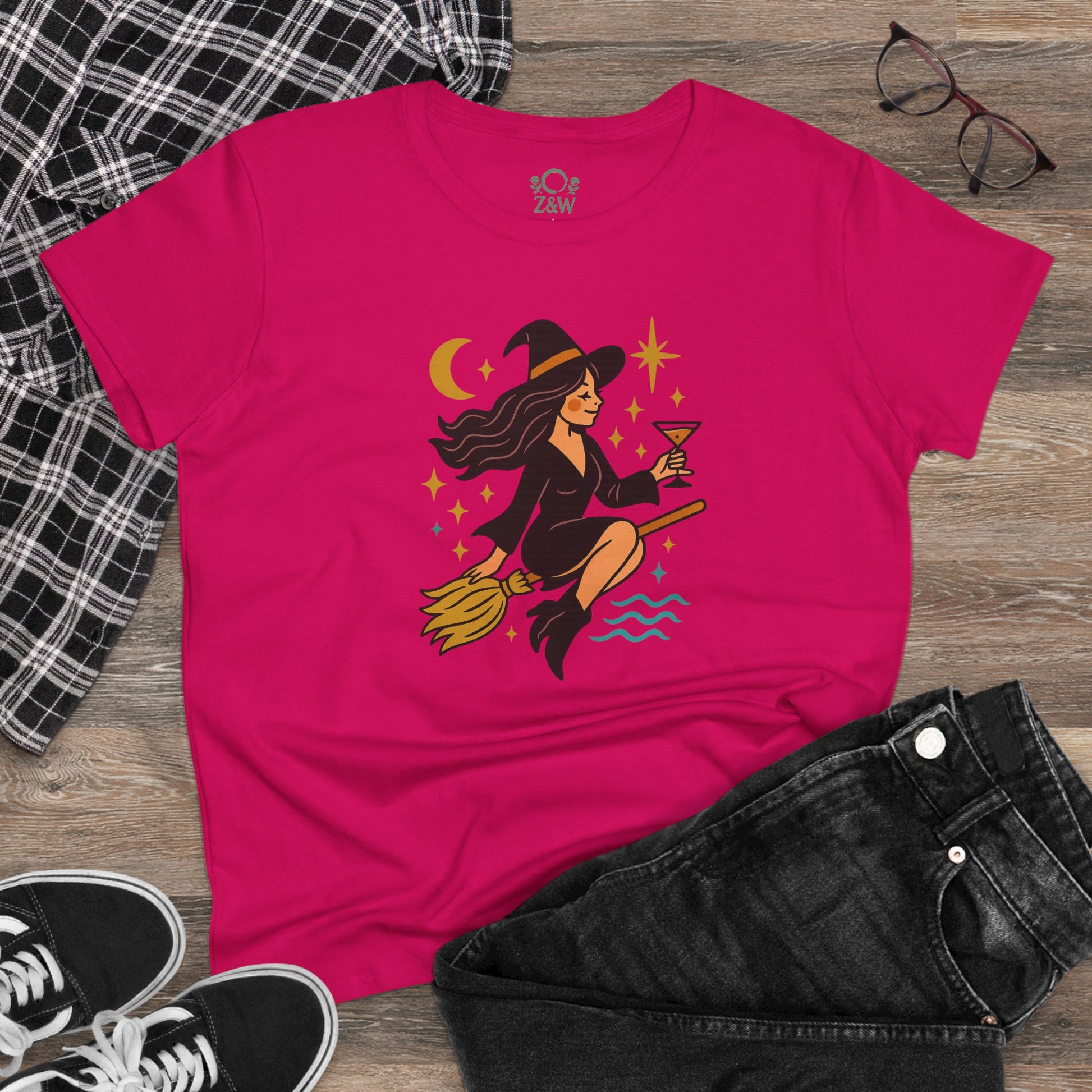 Witchy Night Out Tee laid out with stylish plaid shirt and sunglasses, showcasing the colorful witch design and casual wear.