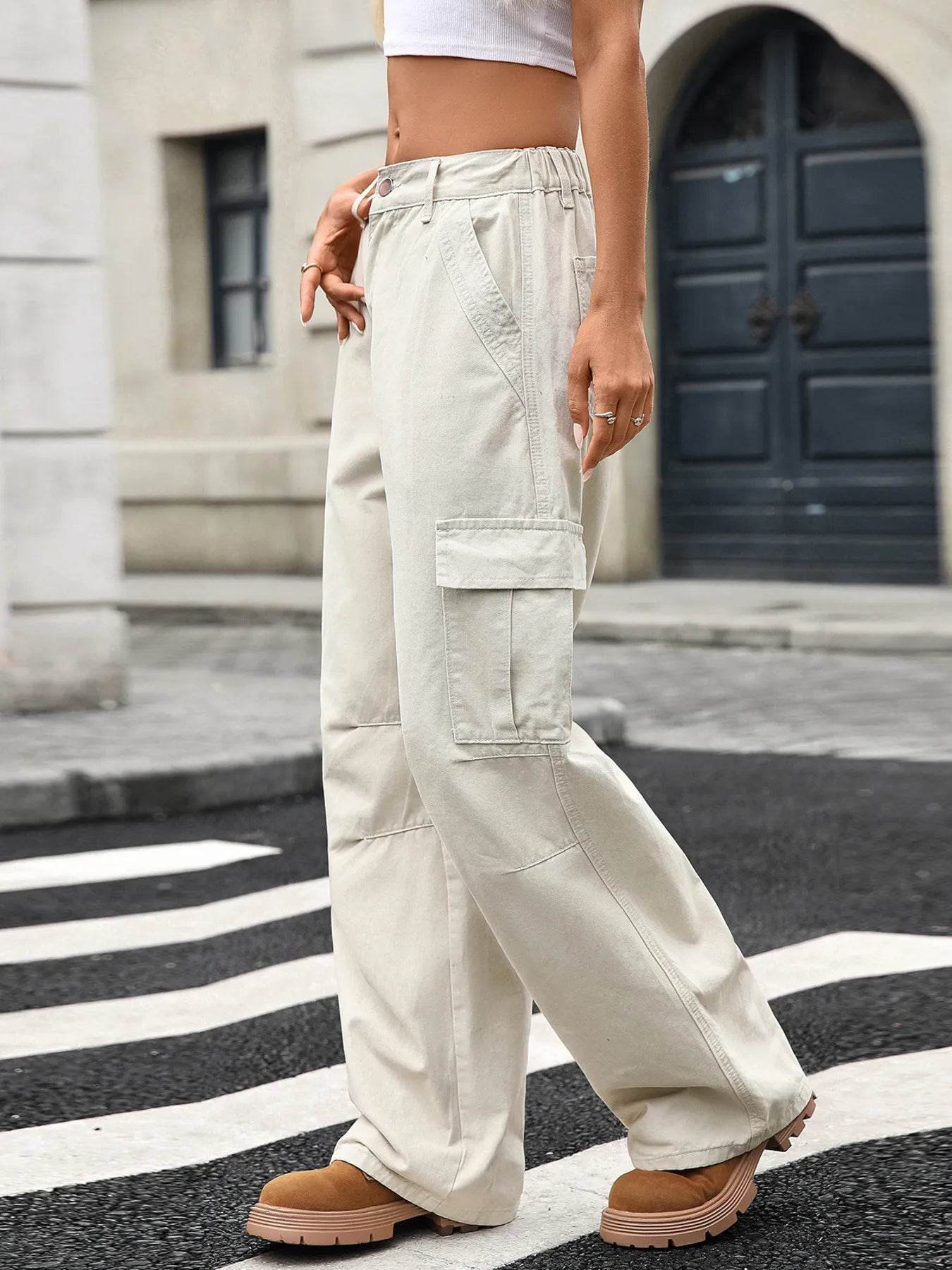 Close-up side view of a model in Wide Leg Cargo Jeans, showcasing the fabric texture and cargo style, complemented by a casual outfit and city surroundings.