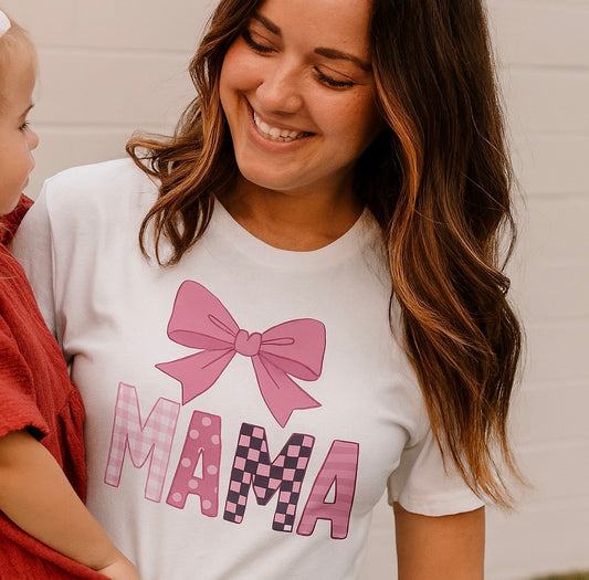 Mama Bow Tee featuring a vibrant pink bow design, worn by a smiling woman, showcasing the seamless 100% cotton material and ribbed collar.
