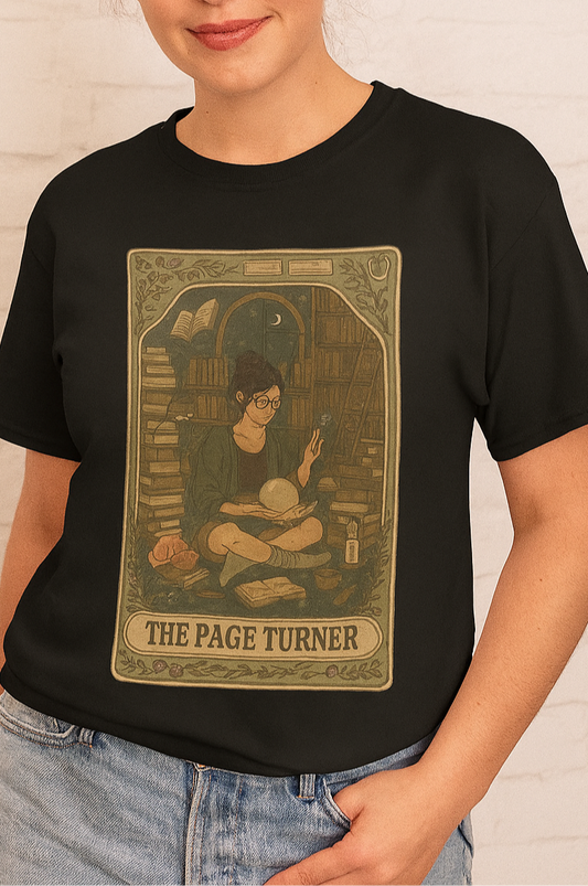 Page Turner Tarot Tee featuring a stylish design on a black shirt, showcasing a character surrounded by books. Available in sizes S to 4XL, this eco-friendly, comfortable t-shirt is perfect for book lovers.