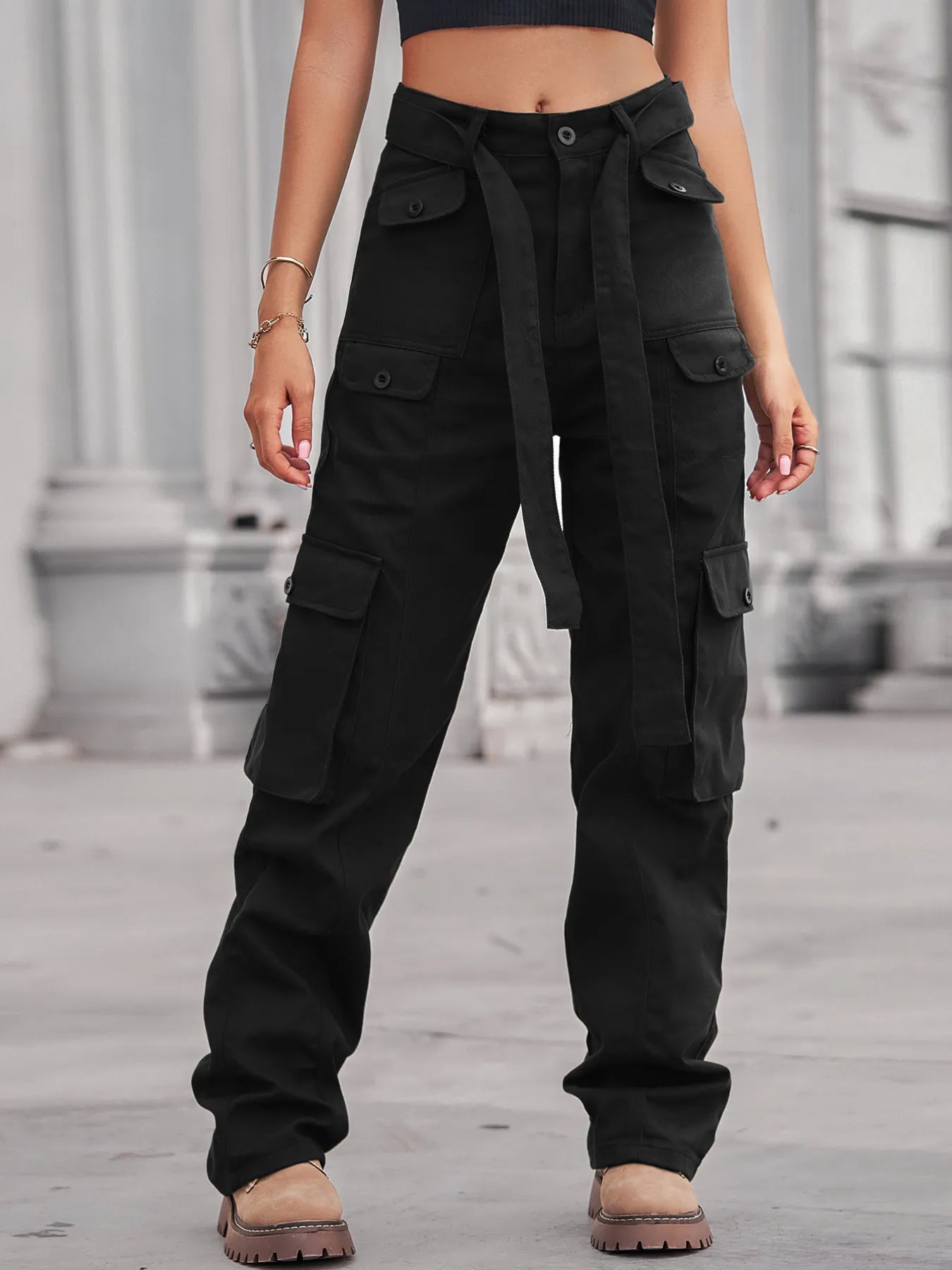 Close-up view of a model in black High-Waisted Multi-Pocket Cargo Jeans, featuring multiple pockets and a tied belt, exuding a trendy look.