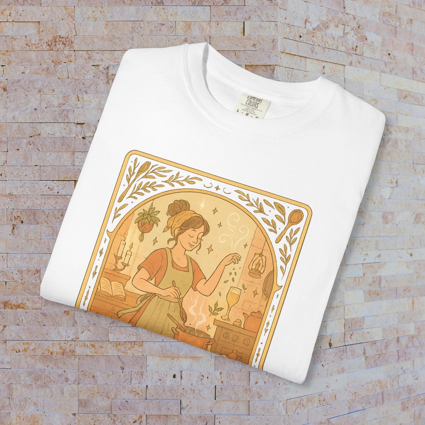 Folded Culinary Queen Tarot Tee in white, highlighting the artistic illustration of a woman cooking with magical elements, crafted from soft cotton and pre-shrunk fabric.