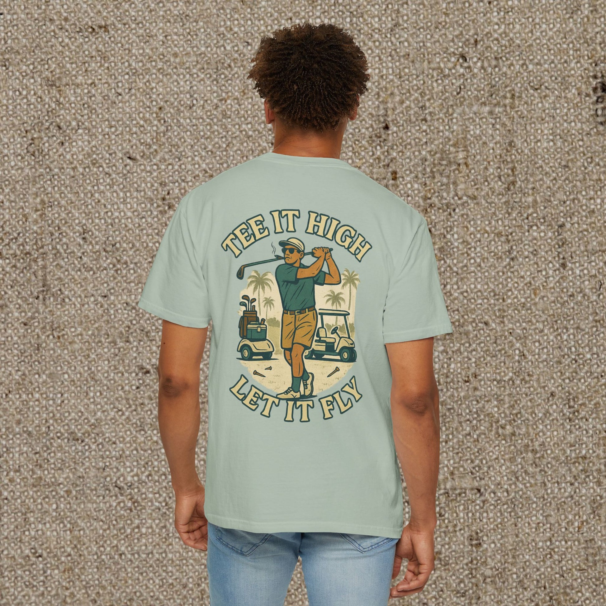 Back view of Tee It High Let It Fly Graphic Tee in light green, featuring a vibrant graphic of a golfer in action with palm trees and golf carts for a casual, fun look.