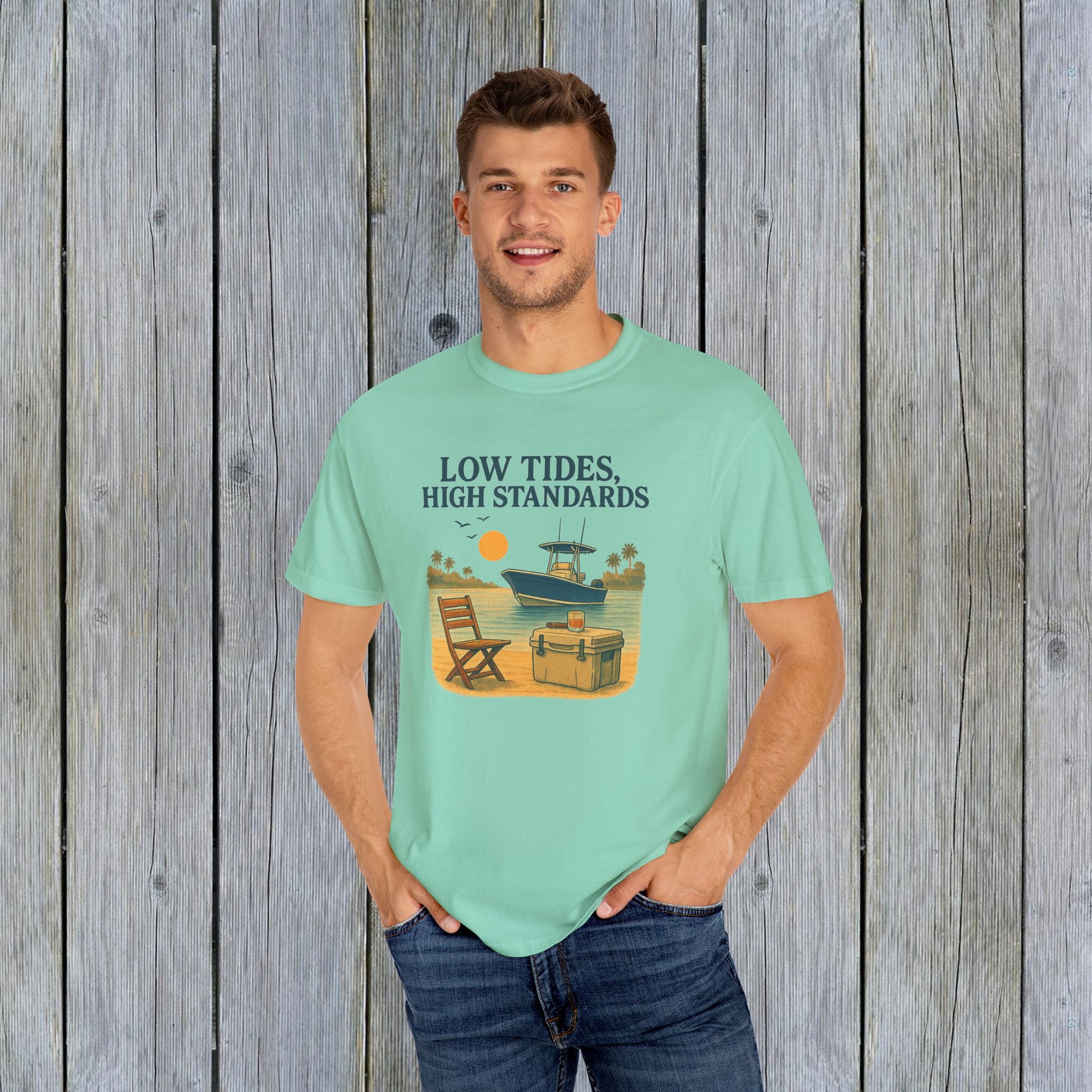 Man wearing the Garment-Dyed Low Tides High Standards T-Shirt in mint green, with a cheerful beach graphic. Great for a relaxed summer look.
