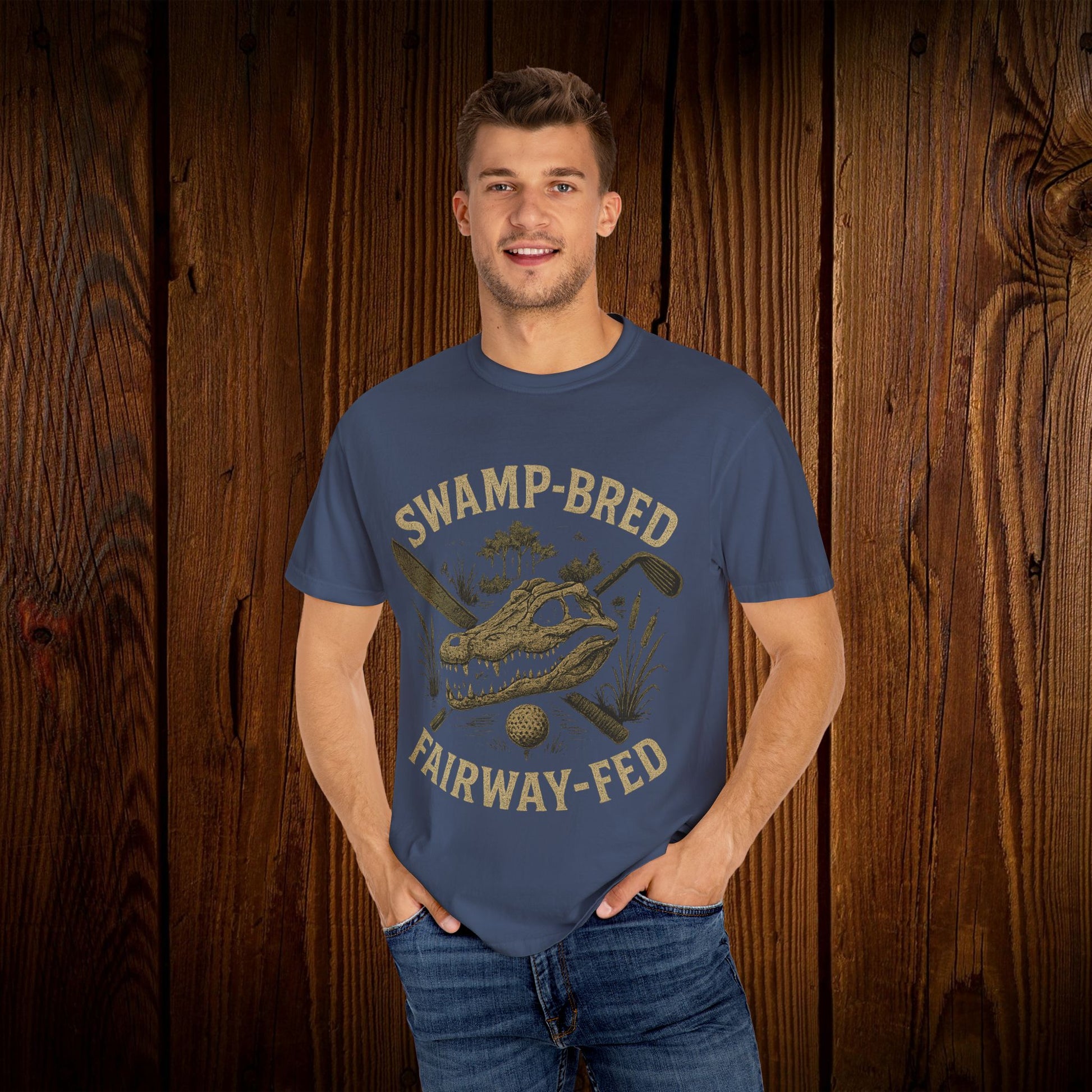 Smiling model wearing the Unisex Swamp-Bred Fairway-Fed Tee in dark blue, featuring a striking design, perfect for showcasing your love for golf and nature.