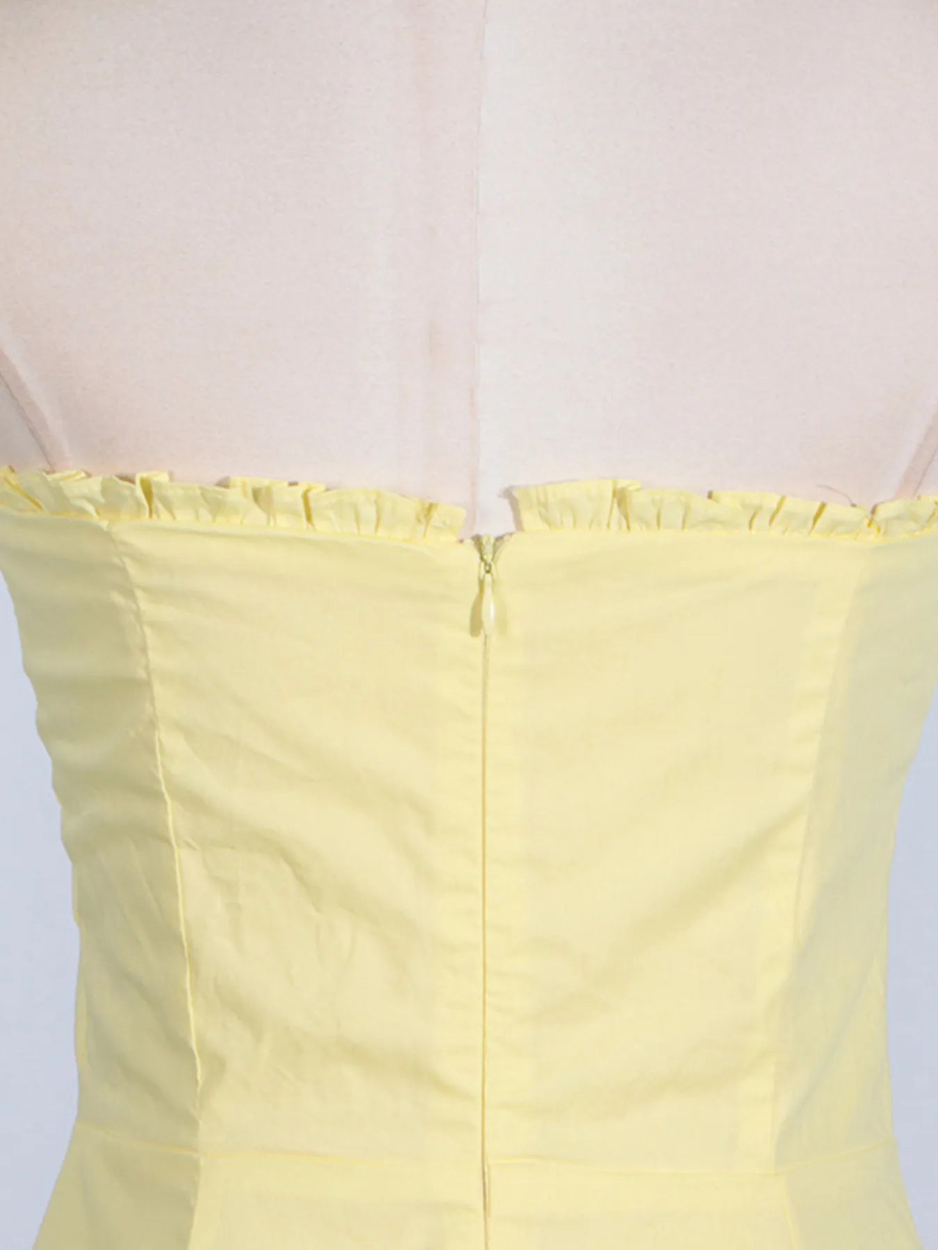 Detailed view of the zip back of the trendy slit sleeveless midi dress, emphasizing the craftsmanship and modern design in a cheerful yellow shade.