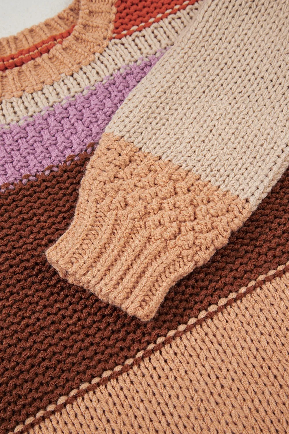 Close-up of the sleeve of the Stylish Colorblock Striped Sweater with Round Neck. This image highlights the intricate knit pattern and color detail, illustrating its 100% acrylic material.