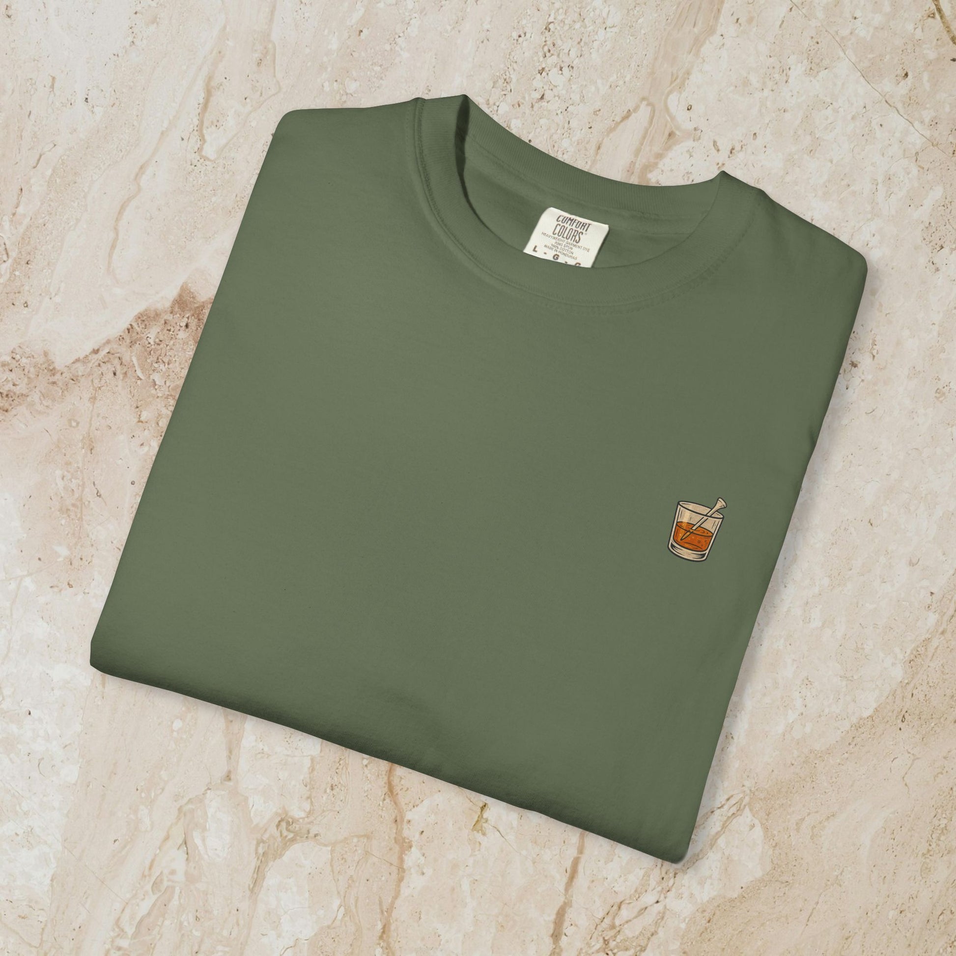 Golden Whiskey Dog Tee folded neatly in olive green, featuring a subtle left chest pocket design with a cocktail illustration.