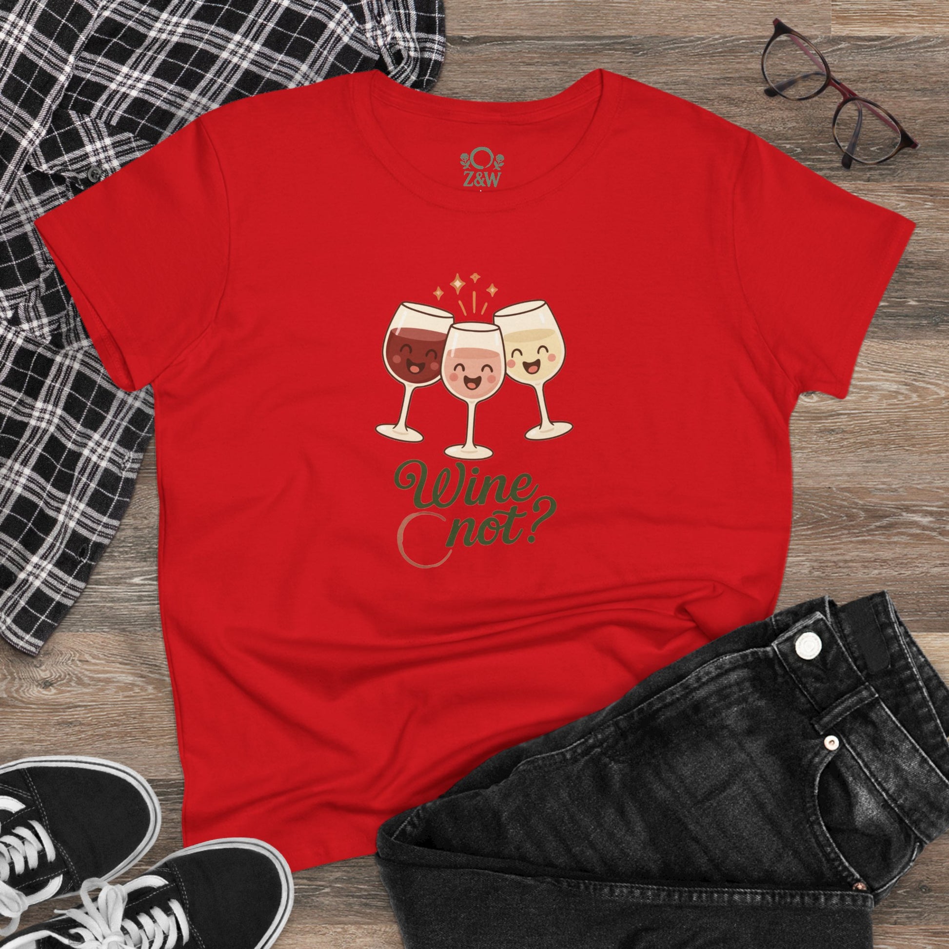 Wine Not Tee styled on a flat lay with black jeans, featuring playful wine glass art on a striking red fabric.