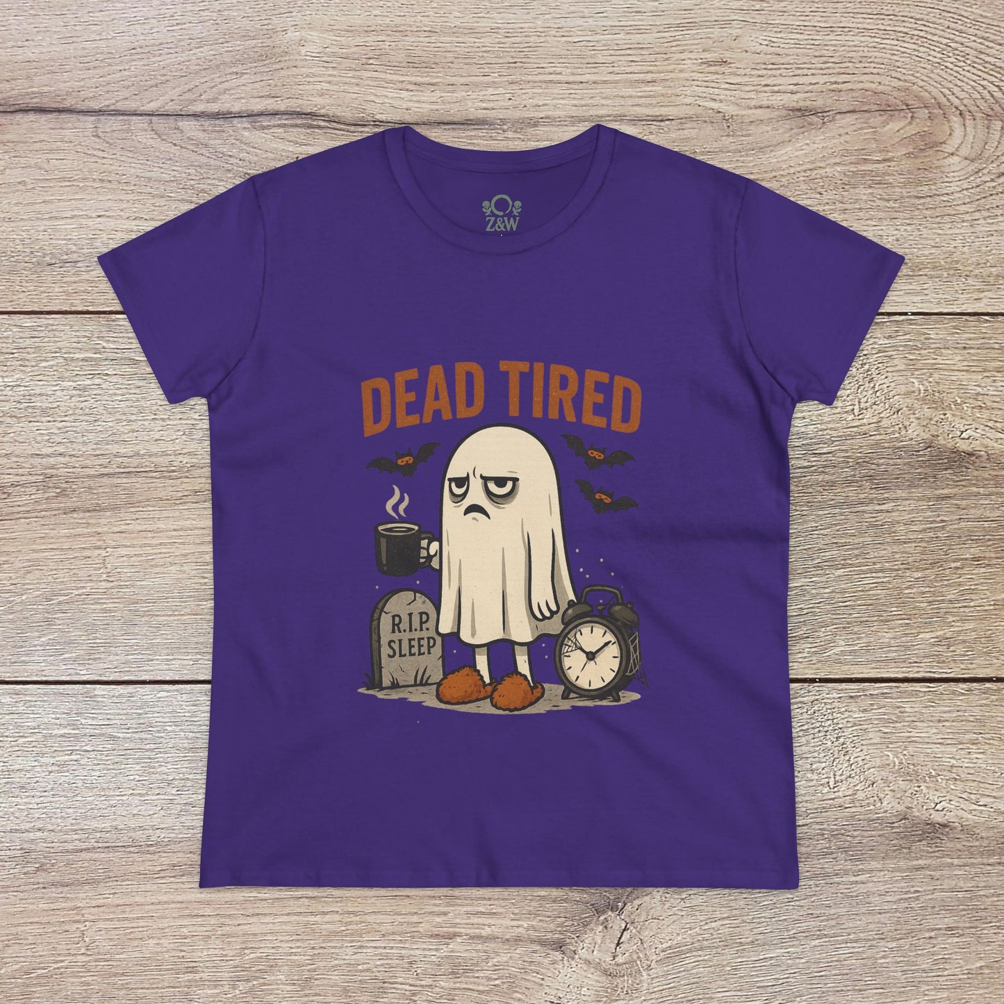 Cute Whimsical Ghost T-Shirt for Halloween in purple, displaying a playful 'DEAD TIRED' illustration with a ghost resting beside a clock, made from comfy 100% cotton for year-round use.