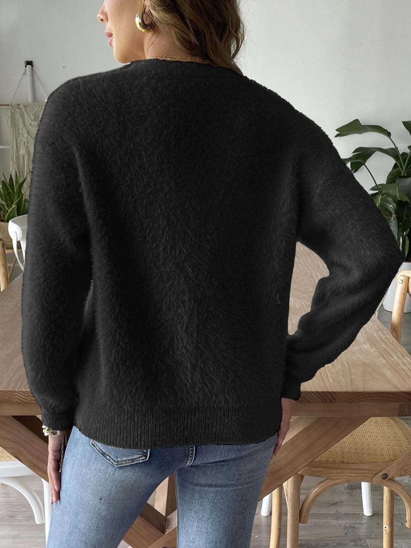 Back view of Trendsi Fuzzy Button-Front Cardigan in black, highlighting the cozy fabric and relaxed fit, styled with blue jeans.