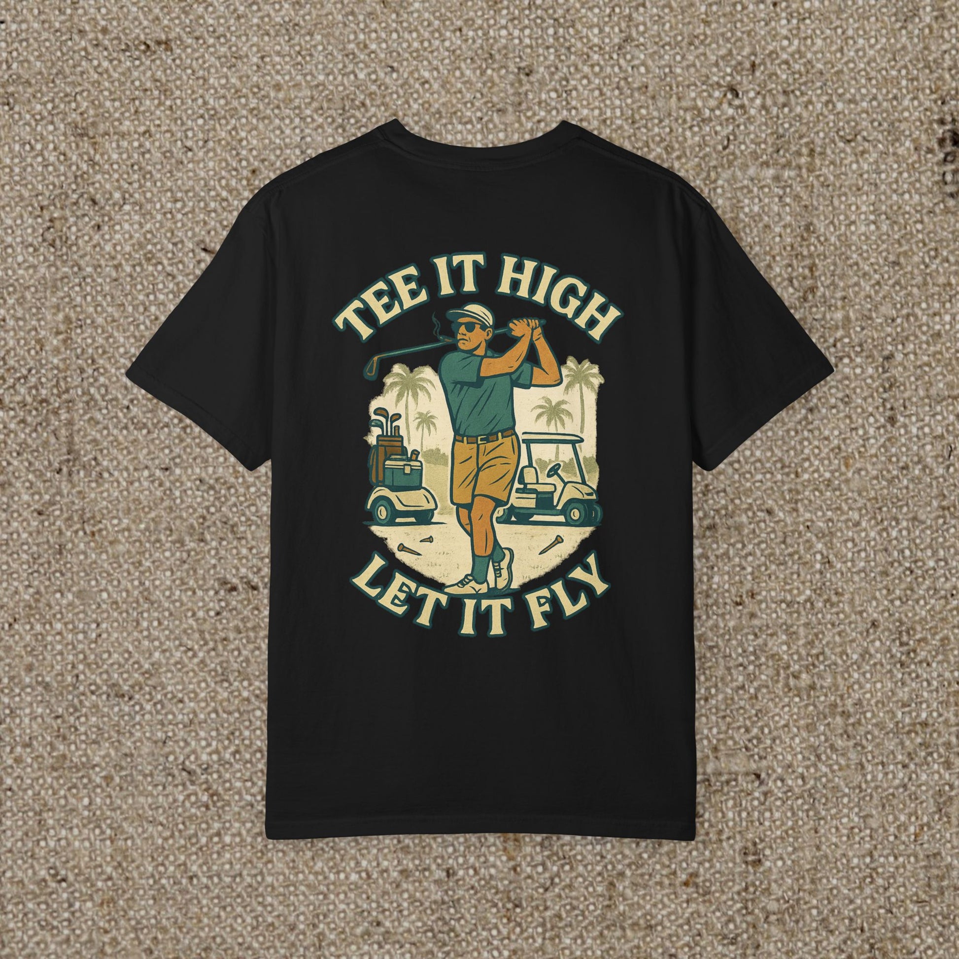 Tee It High Let It Fly Graphic Tee featuring a golfer swinging a club against a tropical background, perfect for golf enthusiasts.