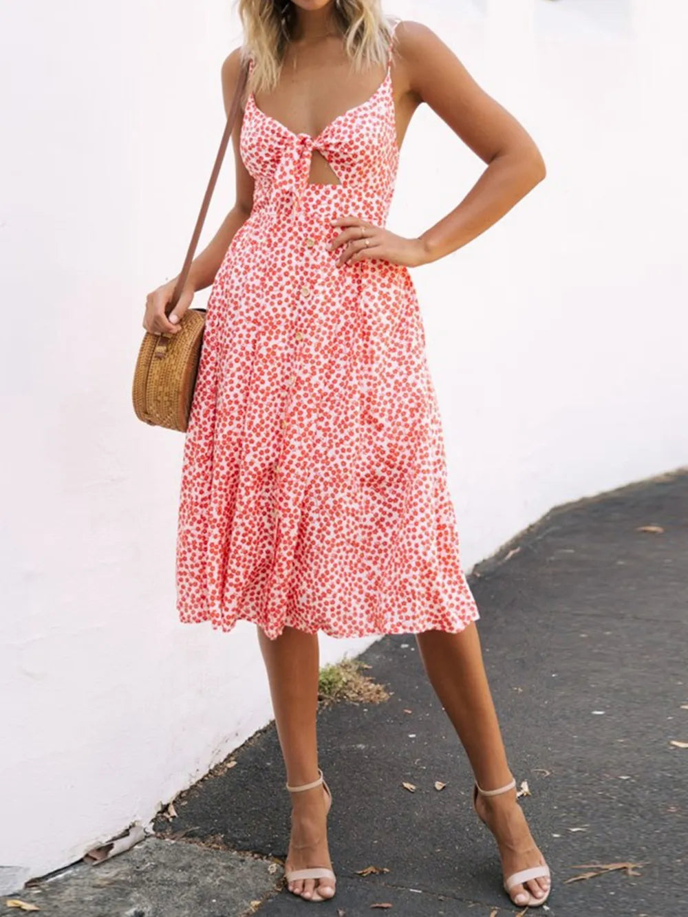 Model wearing a vibrant red floral Cutout Smocked Sweetheart Neck Cami Dress with Decorative Button and Opaque Design, accentuating the stylish silhouette.
