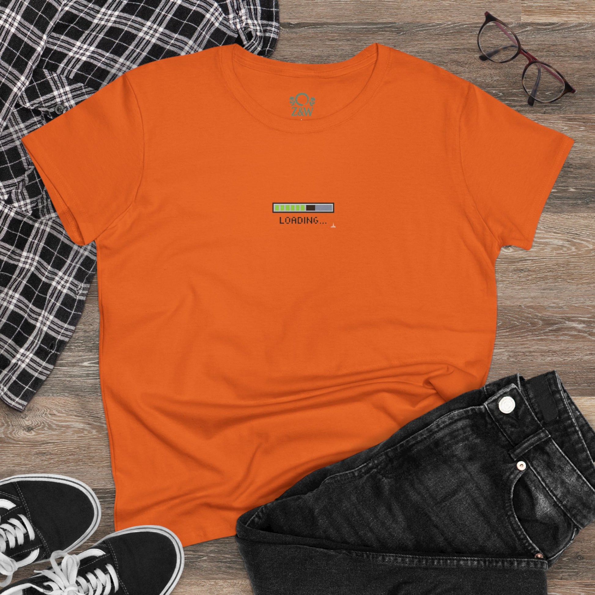 404 Y2K Graphic T-Shirt laid out on a wooden surface, showcasing a vibrant orange design with a loading graphic, ideal for stylish and comfortable wear.