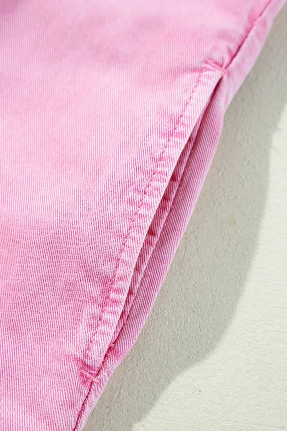 Close-up detail of the button down short sleeve denim dress with pockets, highlighting the garment's pink stitching. Perfect for casual wear and made from 100% cotton.