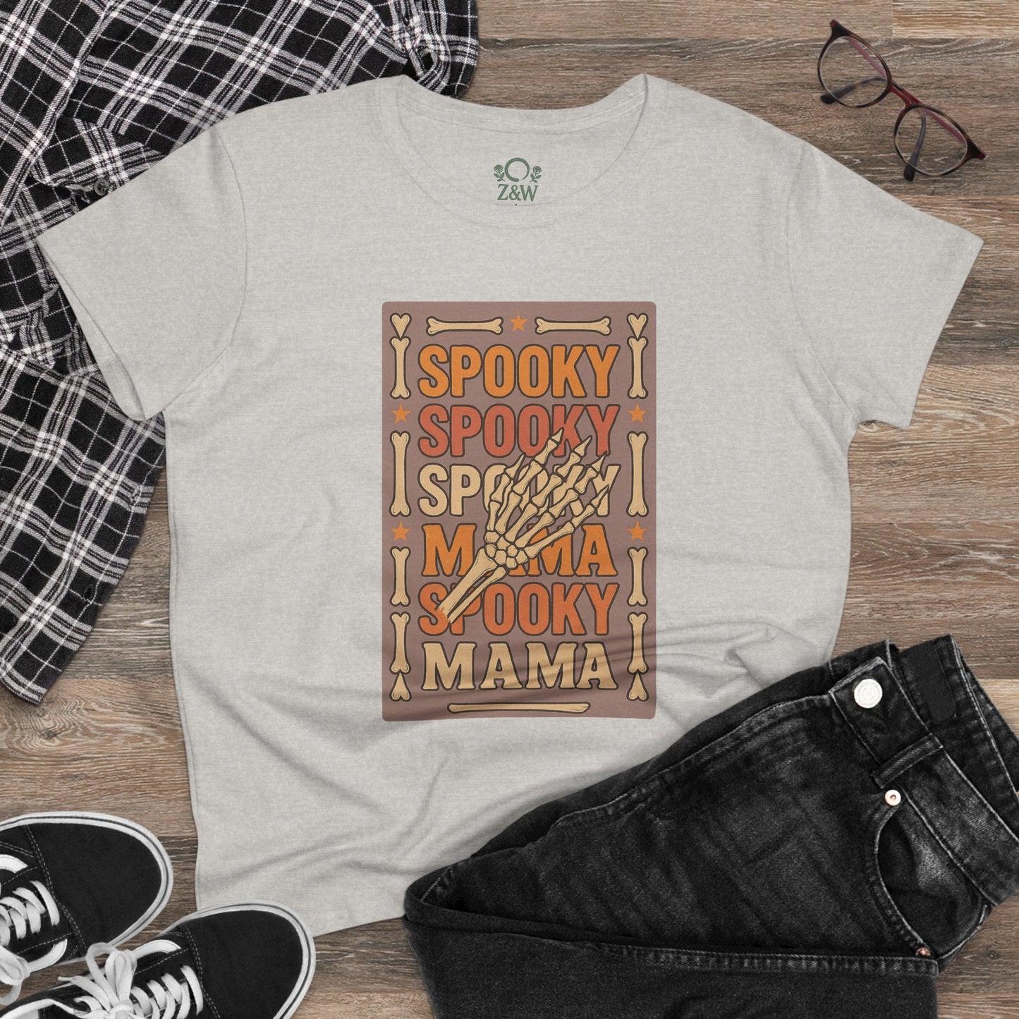 Spooky Mama Tee displayed on a wooden floor, styled with black jeans and sneakers, showcasing its comfortable classic fit.