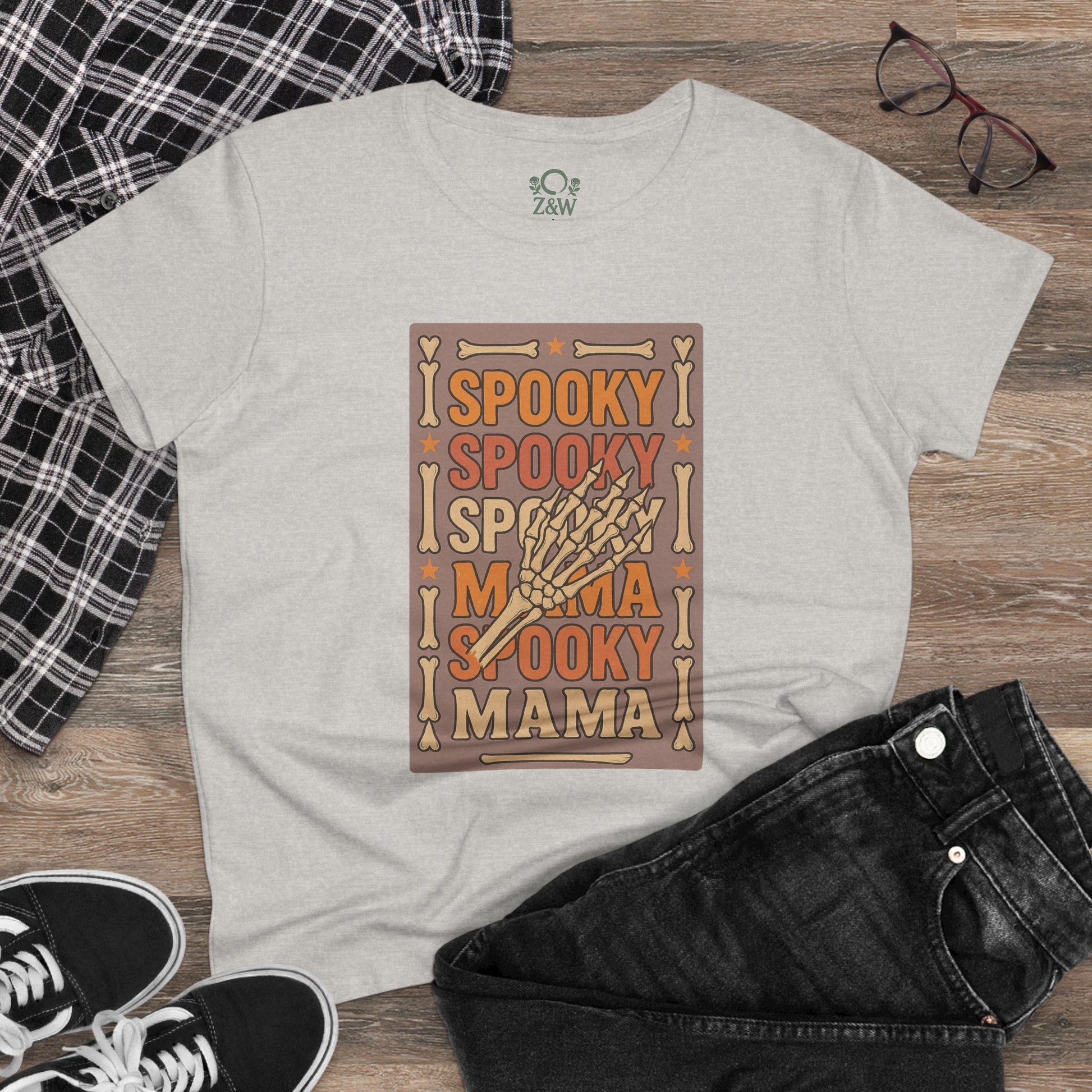 Spooky Mama Tee displayed on a wooden floor, styled with black jeans and sneakers, showcasing its comfortable classic fit.