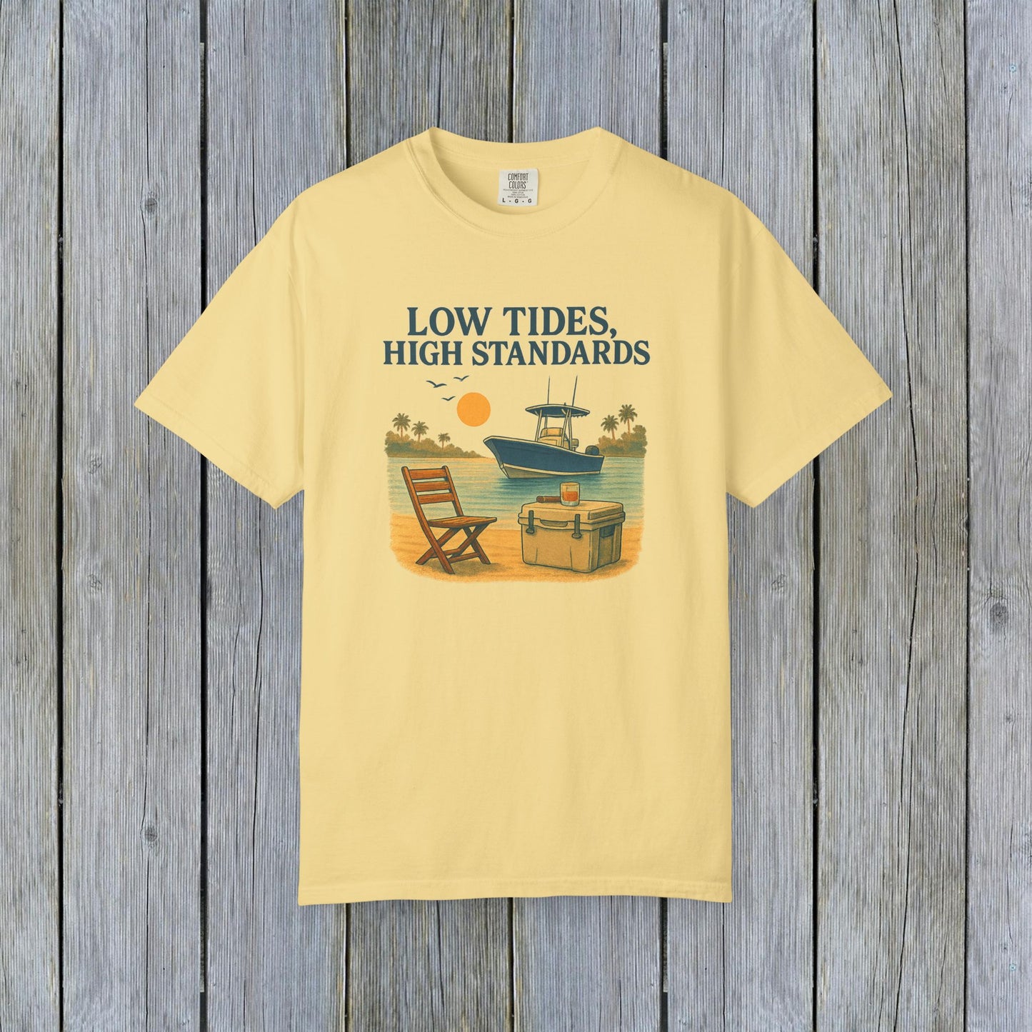 Garment-Dyed Low Tides High Standards T-Shirt in yellow, designed with a relaxing beach scene including a chair, cooler, and boat. Crafted from soft 100% US cotton, this shirt is available in sizes S-4XL.
