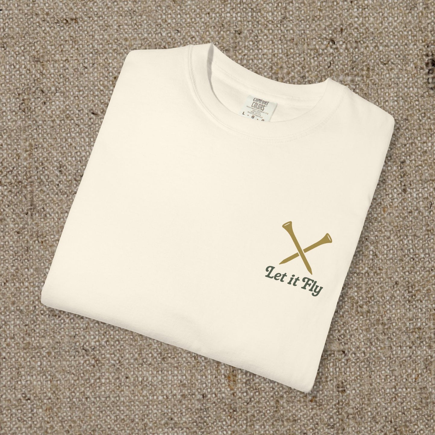 Tee It High Let It Fly Graphic Tee in soft US cotton, showcasing a minimalistic design with crossed golf clubs on a beige background, perfect for a stylish casual look.