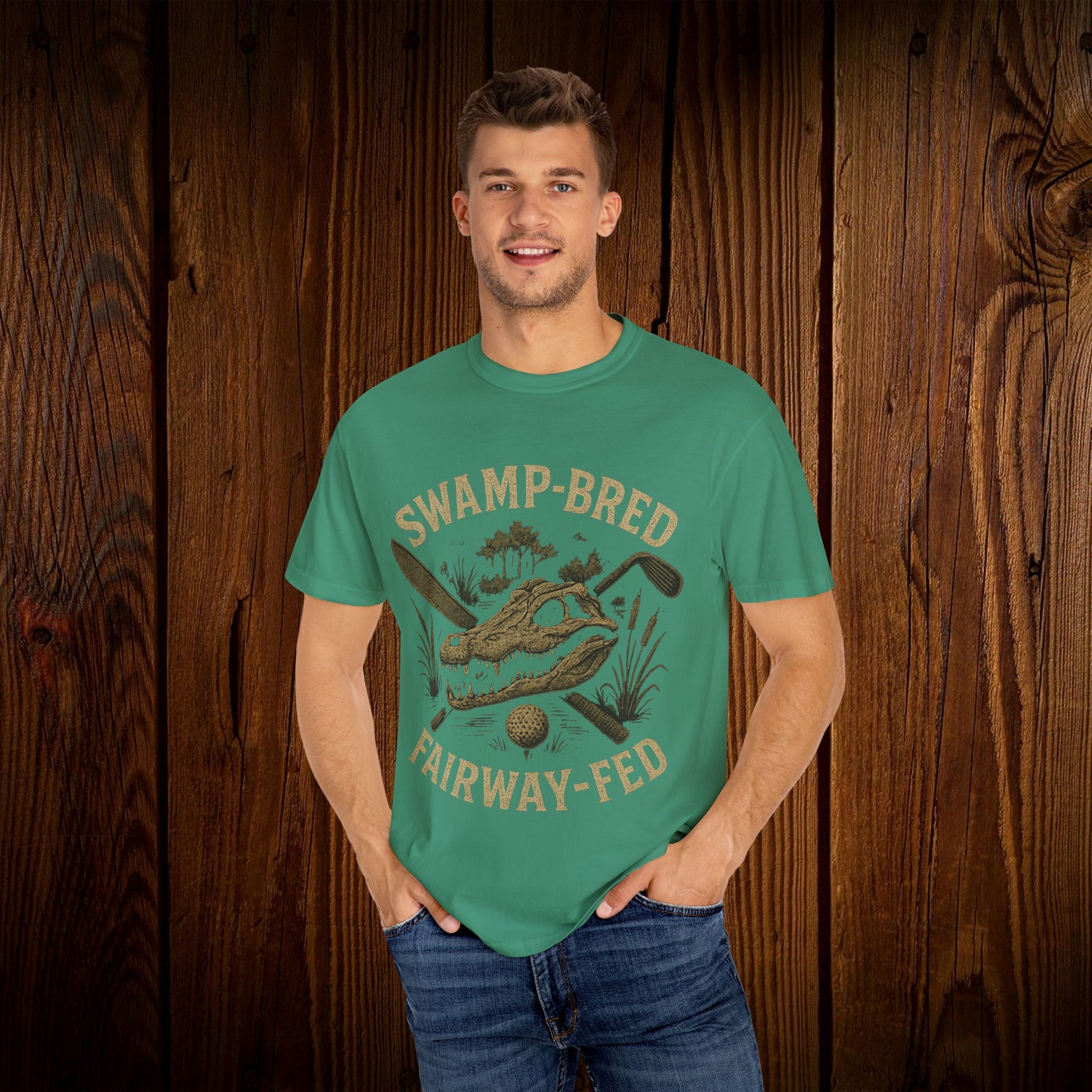 Model posing in the Unisex Swamp-Bred Fairway-Fed Tee in teal, featuring a golf-themed graphic. The shirt embodies comfort and style, perfect for everyday wear or on the golf course.