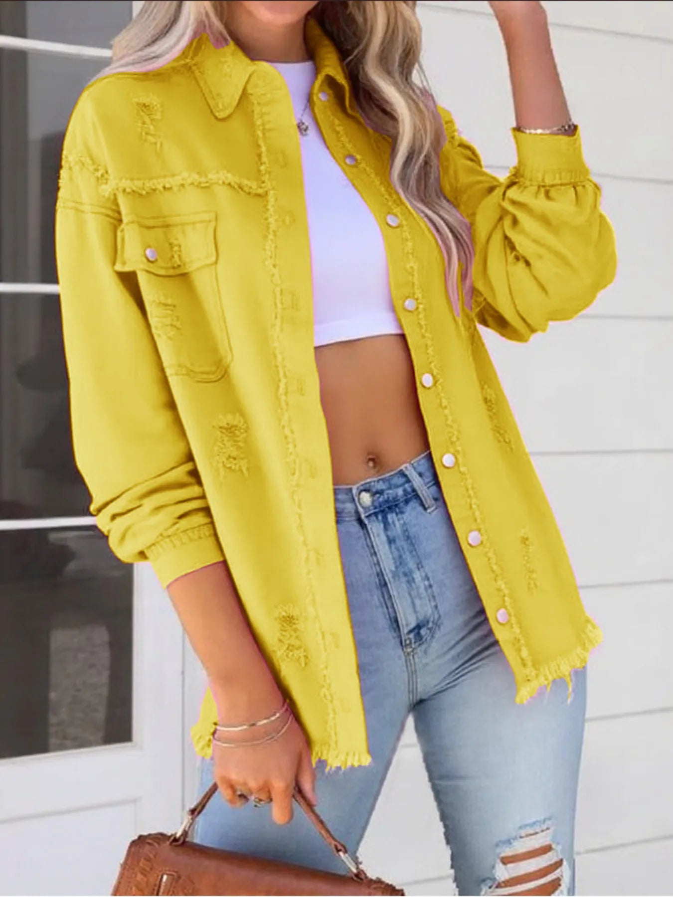 Vibrant and trendy oversized distressed denim jacket with frayed edges and buttoned pockets, featured in a bold yellow color for a casual outfit.