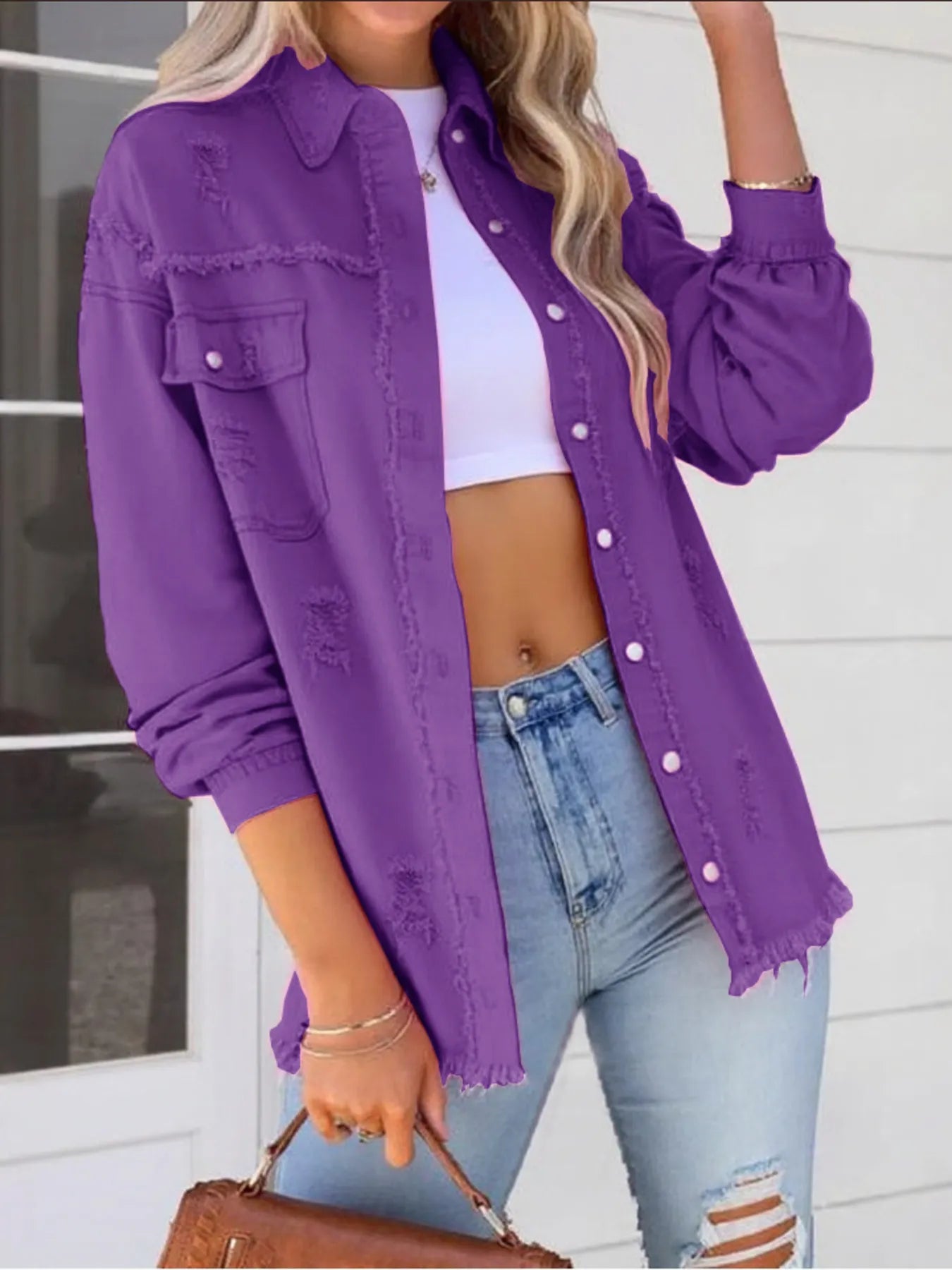 Fashionable model in an oversized distressed denim jacket with frayed edges and buttoned pockets, confidently posing in light wash jeans for a trendy casual outfit.
