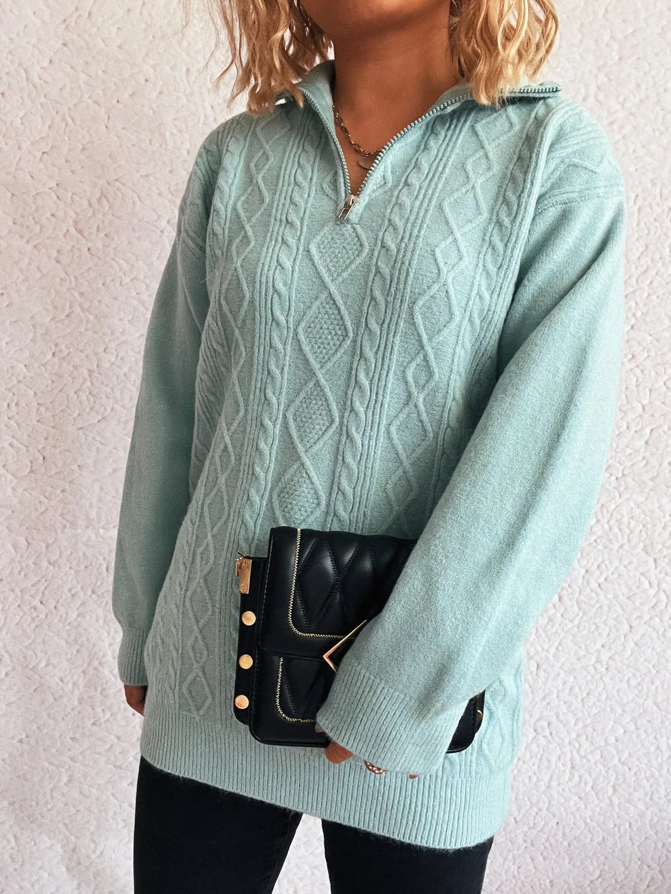 Model wearing the Cozy Cable-Knit Texture Zip Collar Long Sleeve Sweater in a soft blue shade, paired with a stylish black handbag.