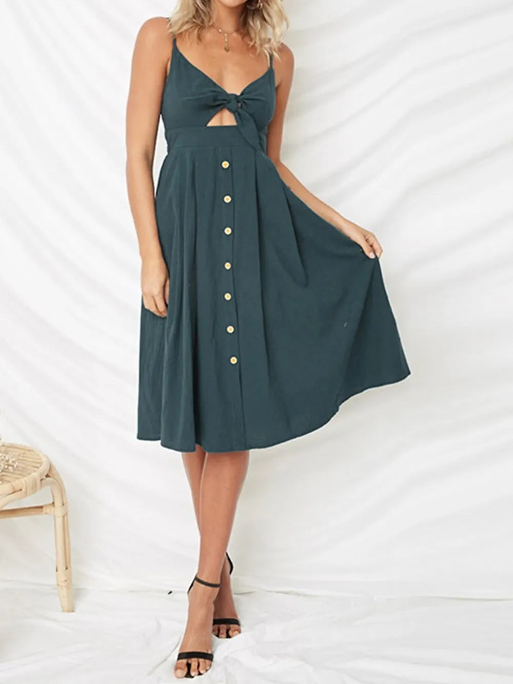 Model elegantly displaying a dark green Cutout Smocked Sweetheart Neck Cami Dress with Decorative Button and Opaque Design, featuring a flared skirt.