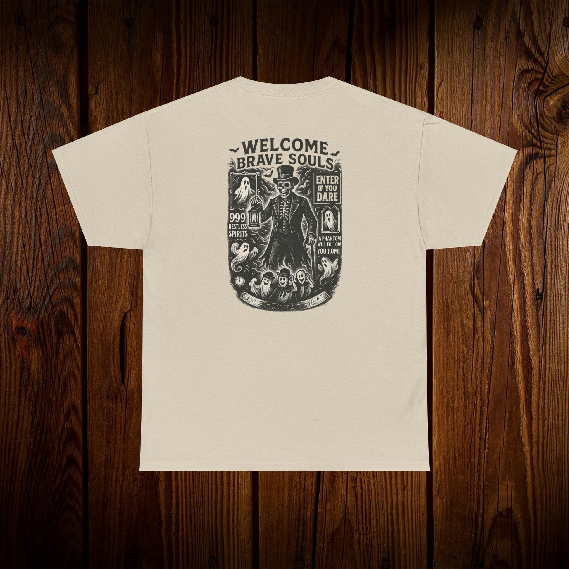 Back view of a Spooky Halloween Graphic Tee with a unique design stating 'Welcome Brave Souls', perfect for Halloween festivities, set on a wooden surface.