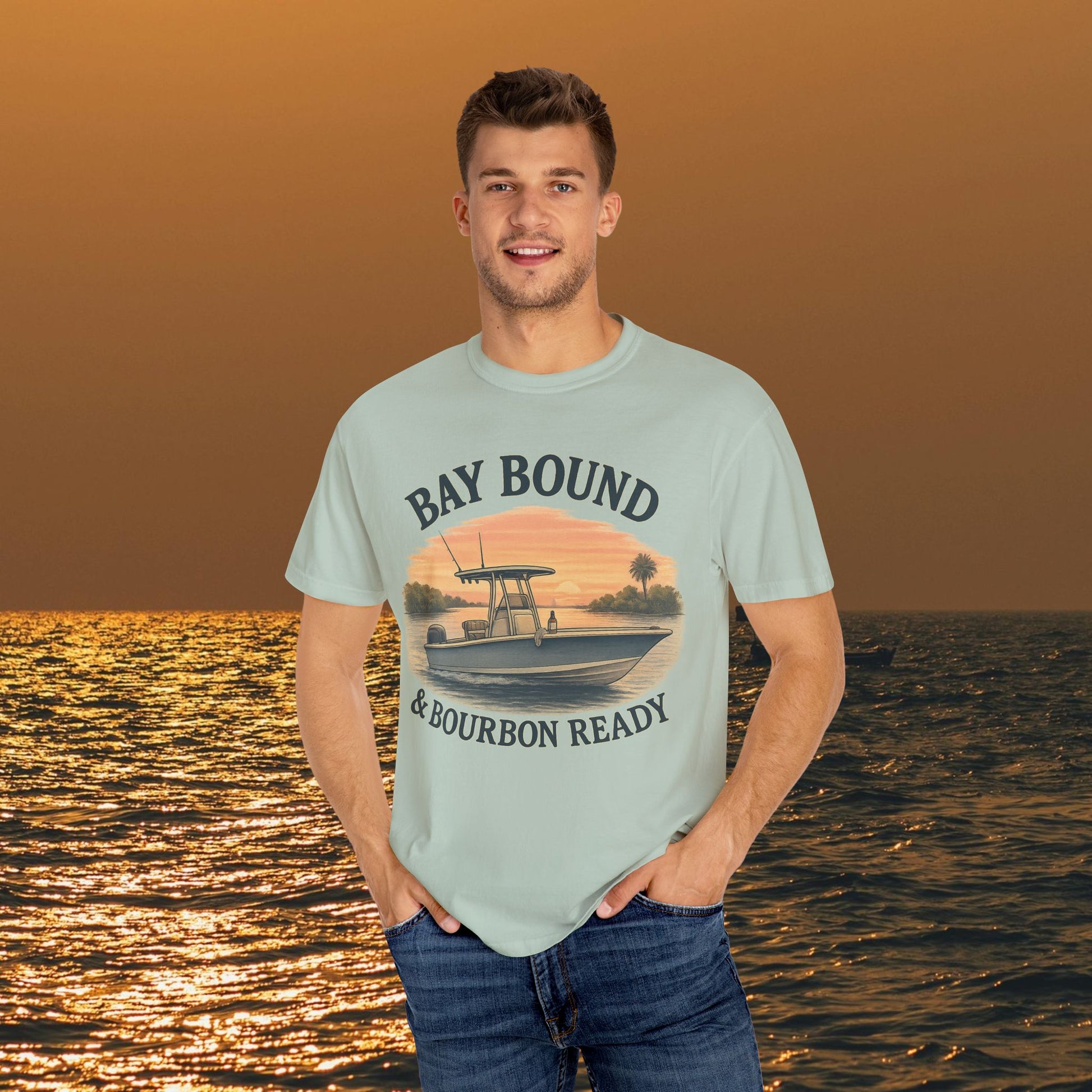 Model wearing the Bay Bound T-Shirt for Summer, with a boat design, set against a beautiful sunset over water, suitable for fishing and beach lovers.