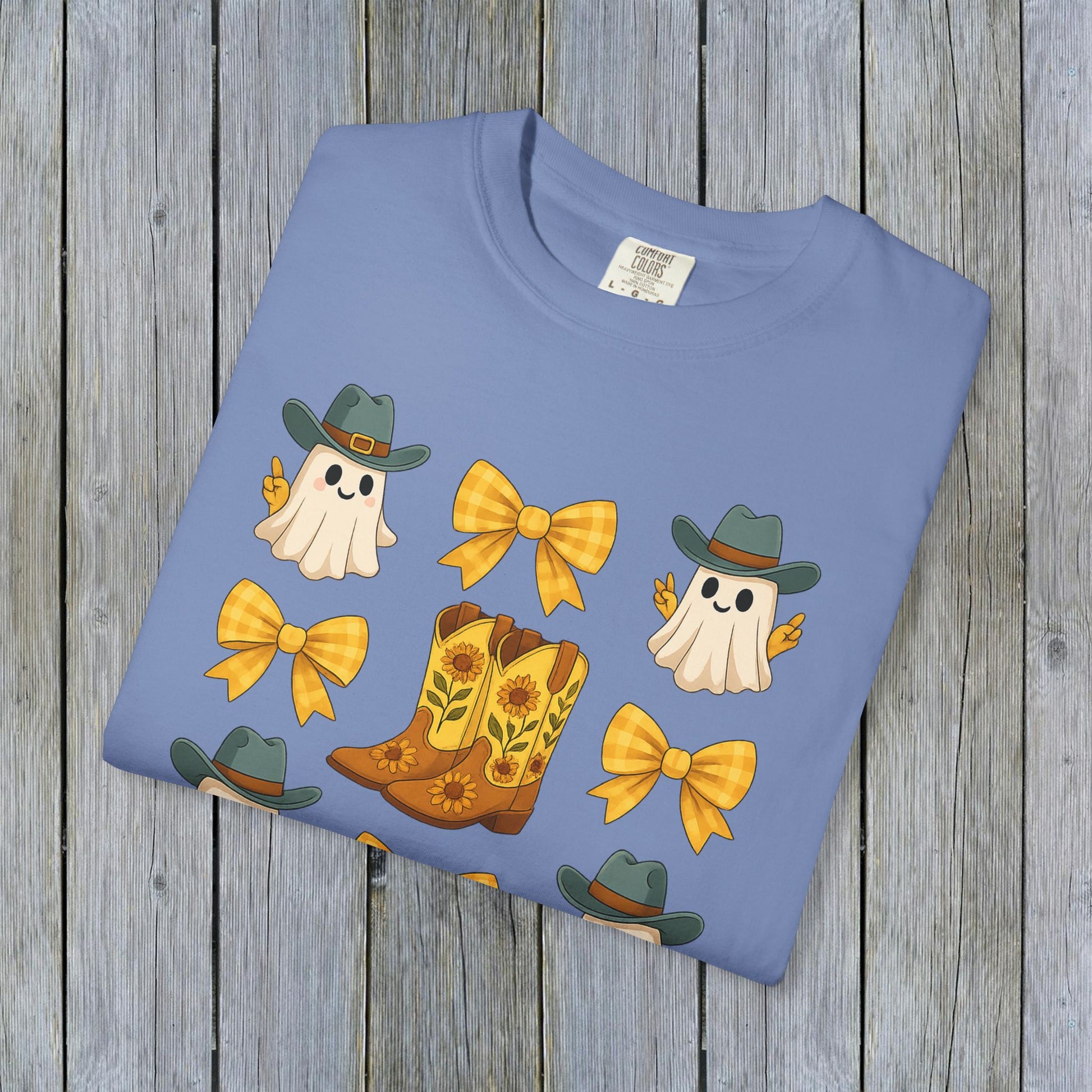 Folded Cute Halloween T-Shirt with vibrant ghosts and cowboy boots design, highlighting eco-friendly fabric. Perfect for unisex fall fashion enthusiasts.