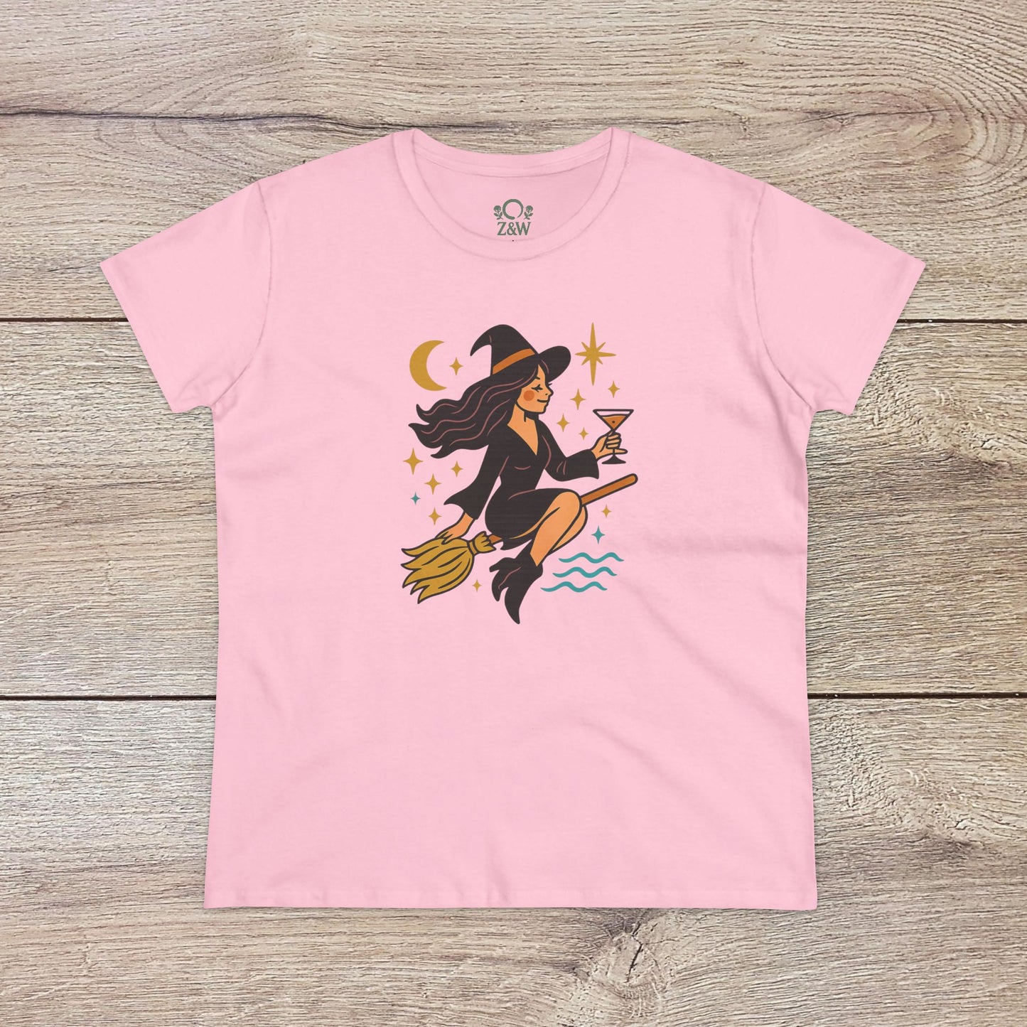 Witchy Night Out Tee in soft pink illustrated with a lively witch on a broomstick, accompanied by celestial designs, made from environmentally friendly, ethically sourced cotton.
