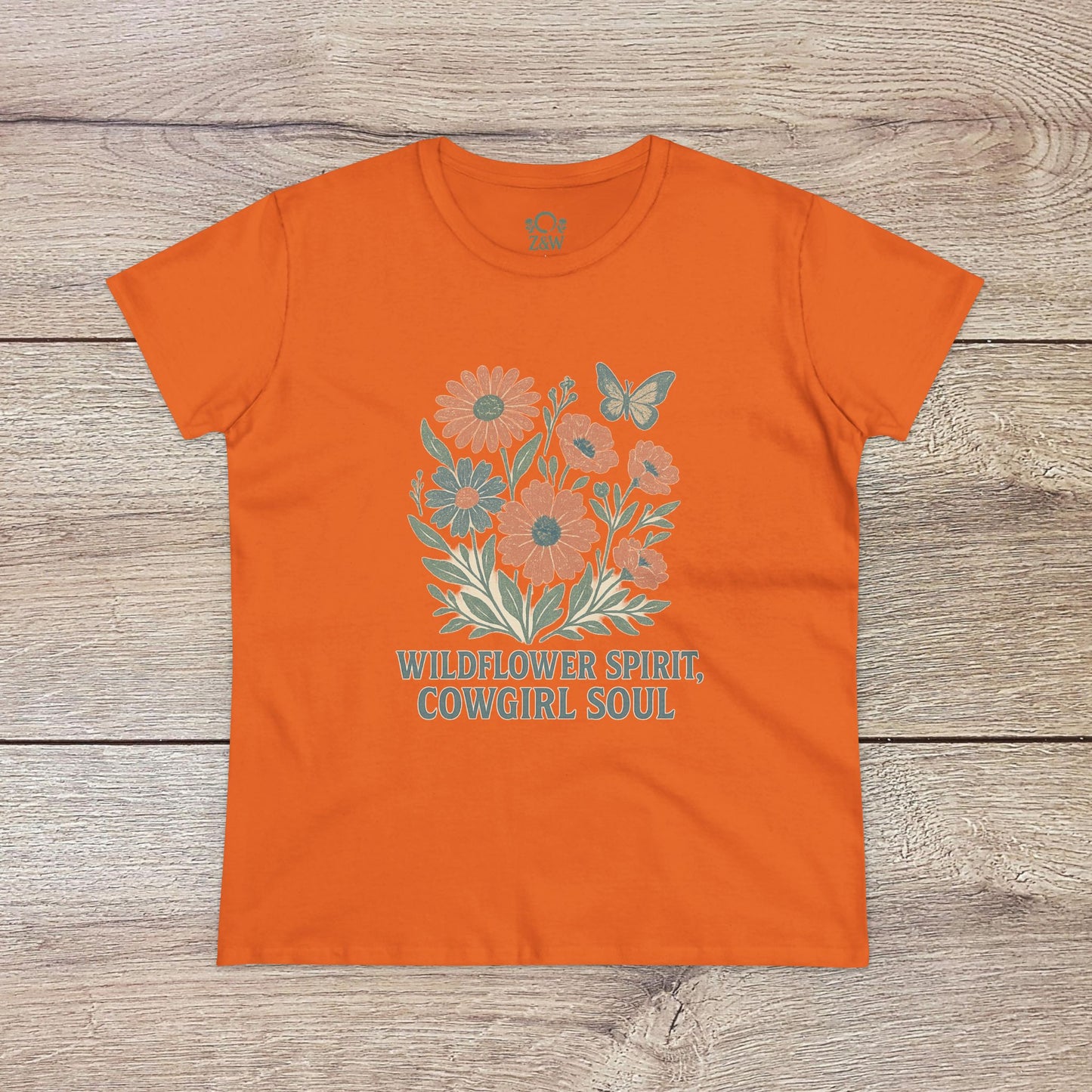 Wildflower Spirit Cotton Tee in orange featuring a vibrant floral graphic and the phrase 'Wildflower Spirit, Cowgirl Soul', crafted for comfort.
