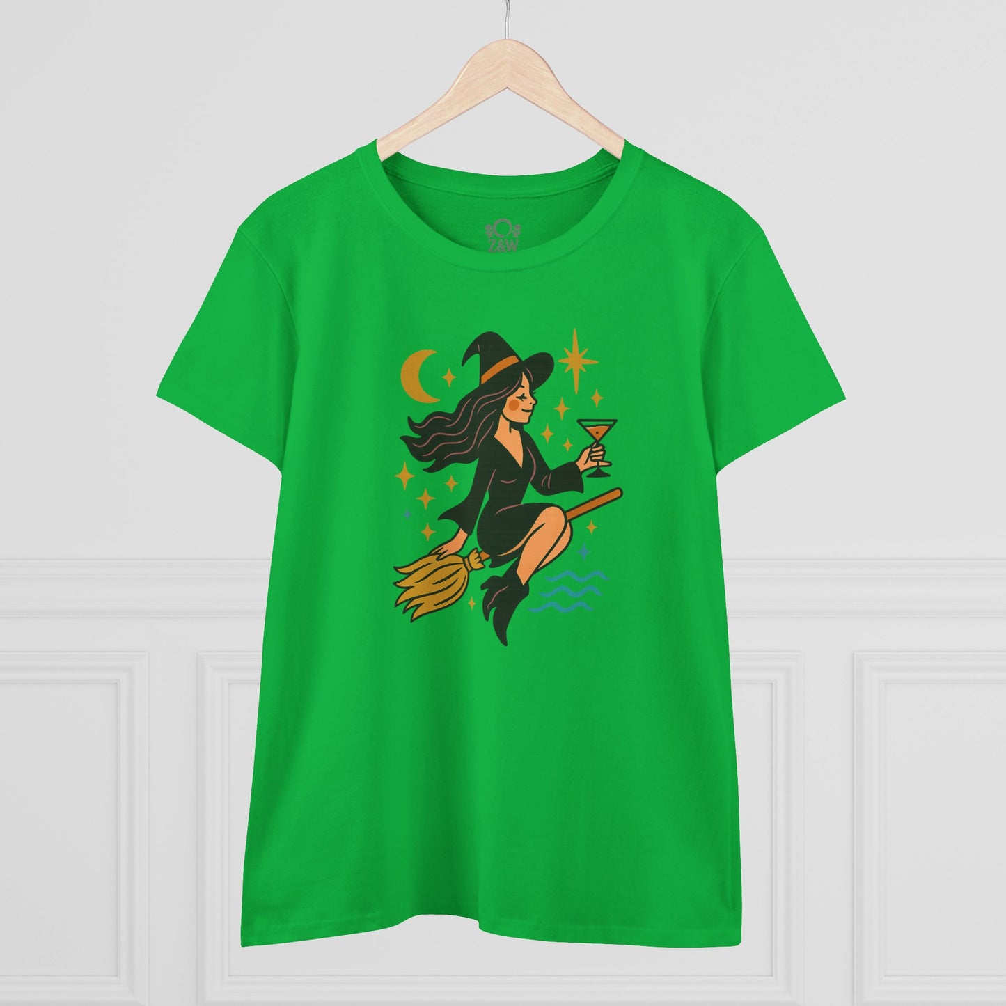 Witchy Night Out Tee in green displayed hanging on a hanger, featuring a fun design of a witch with a cocktail, perfect for stylish and ethically made fashion.