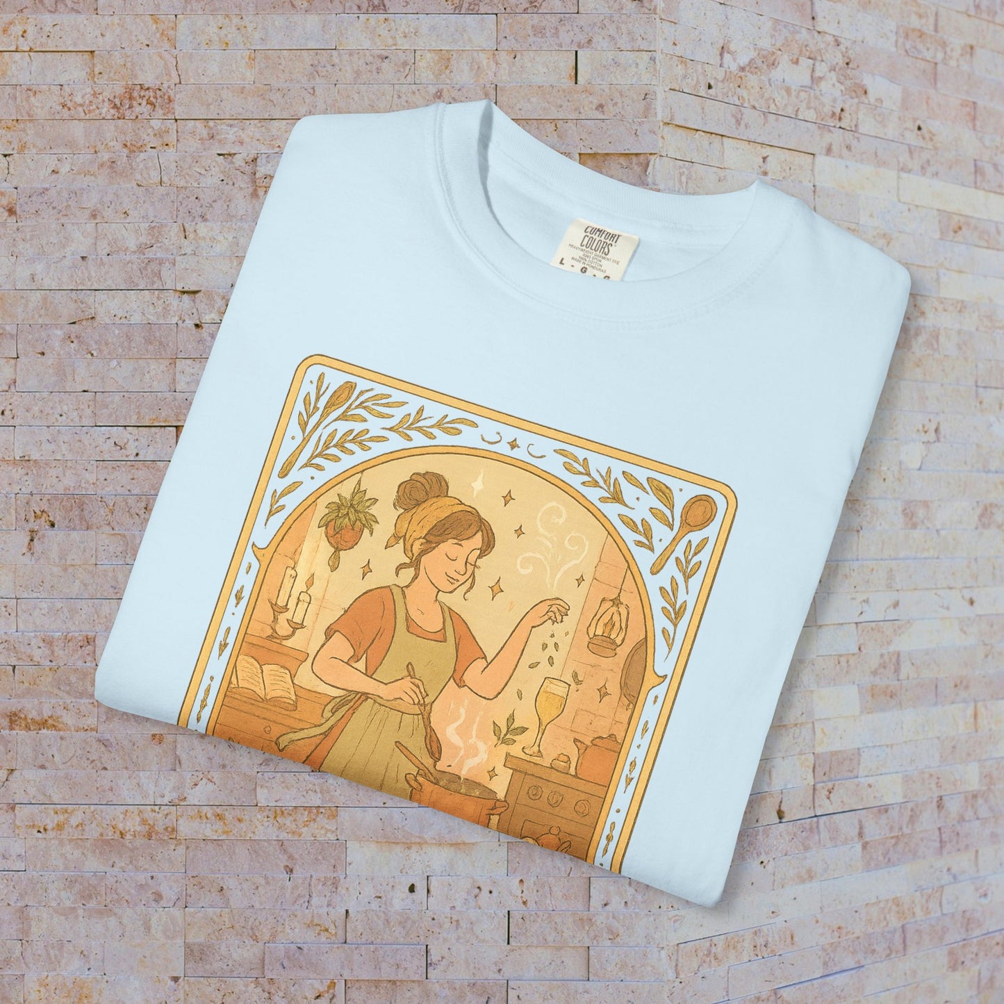 Folded Culinary Queen Tarot Tee in light blue, displaying a beautiful graphic of a culinary scene with a woman and whimsical elements, made from high-quality cotton and perfect for all sizes.