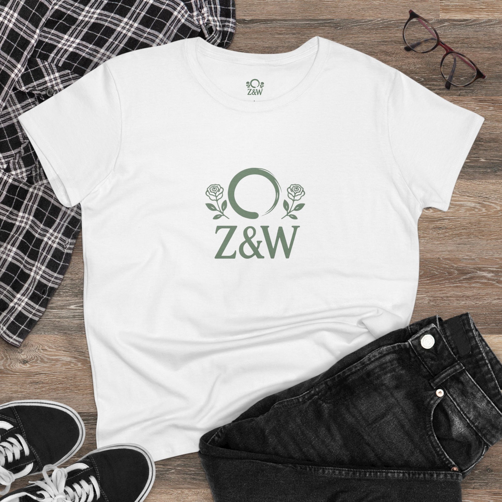 ZenAndWhiskey Classic 100% Cotton Tee laid flat on a wooden surface with casual black jeans and plaid shirt, illustrating versatility for everyday wear.