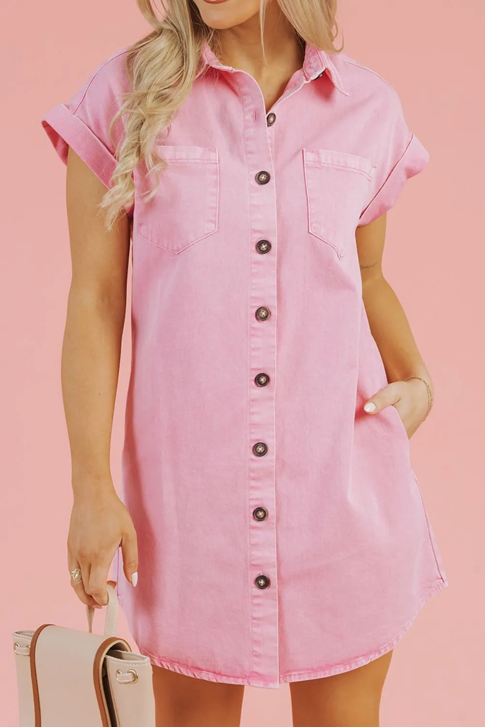 Model showcasing a Button Down Short Sleeve Denim Dress with Pockets in pink, styled with a handbag, demonstrating versatility and fashion.