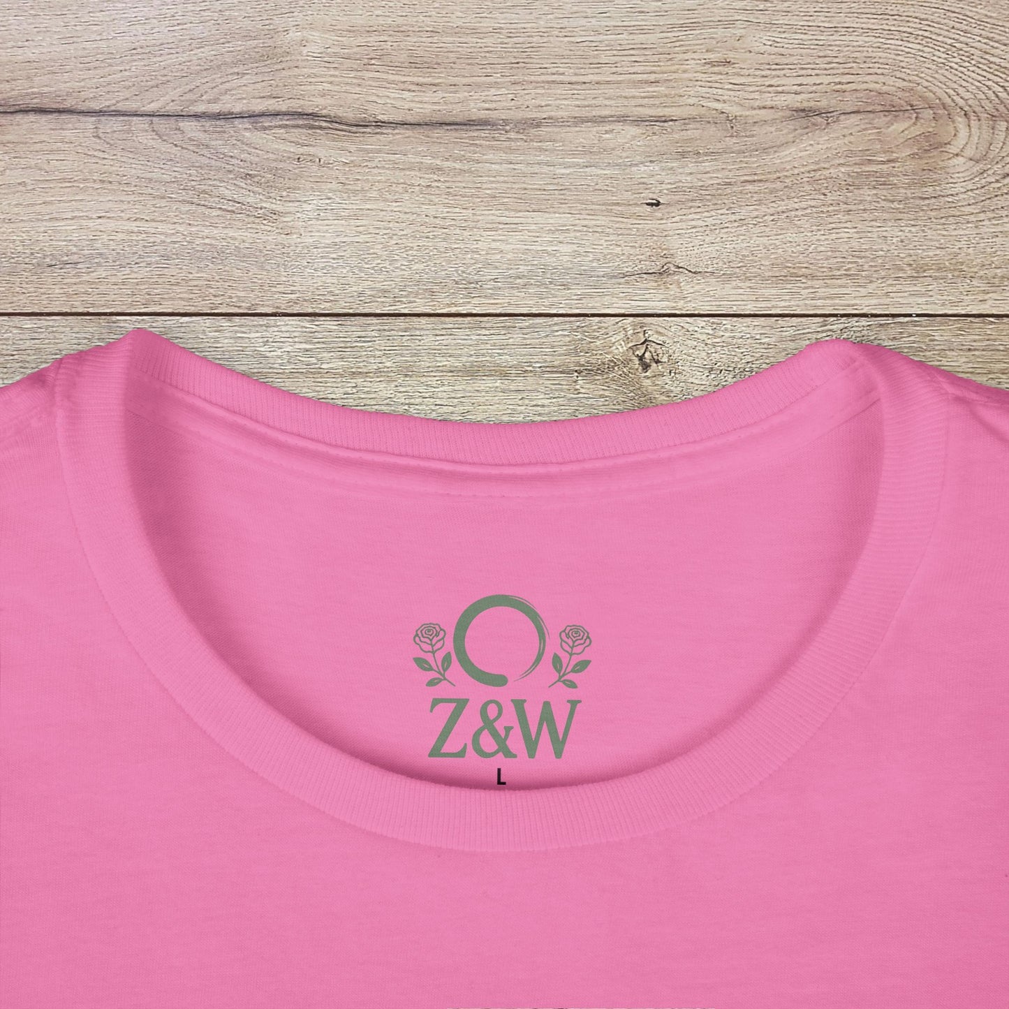 Wildflowers T-Shirt featuring a ribbed collar and a logo on the back, presented in soft pink color on a wooden table.