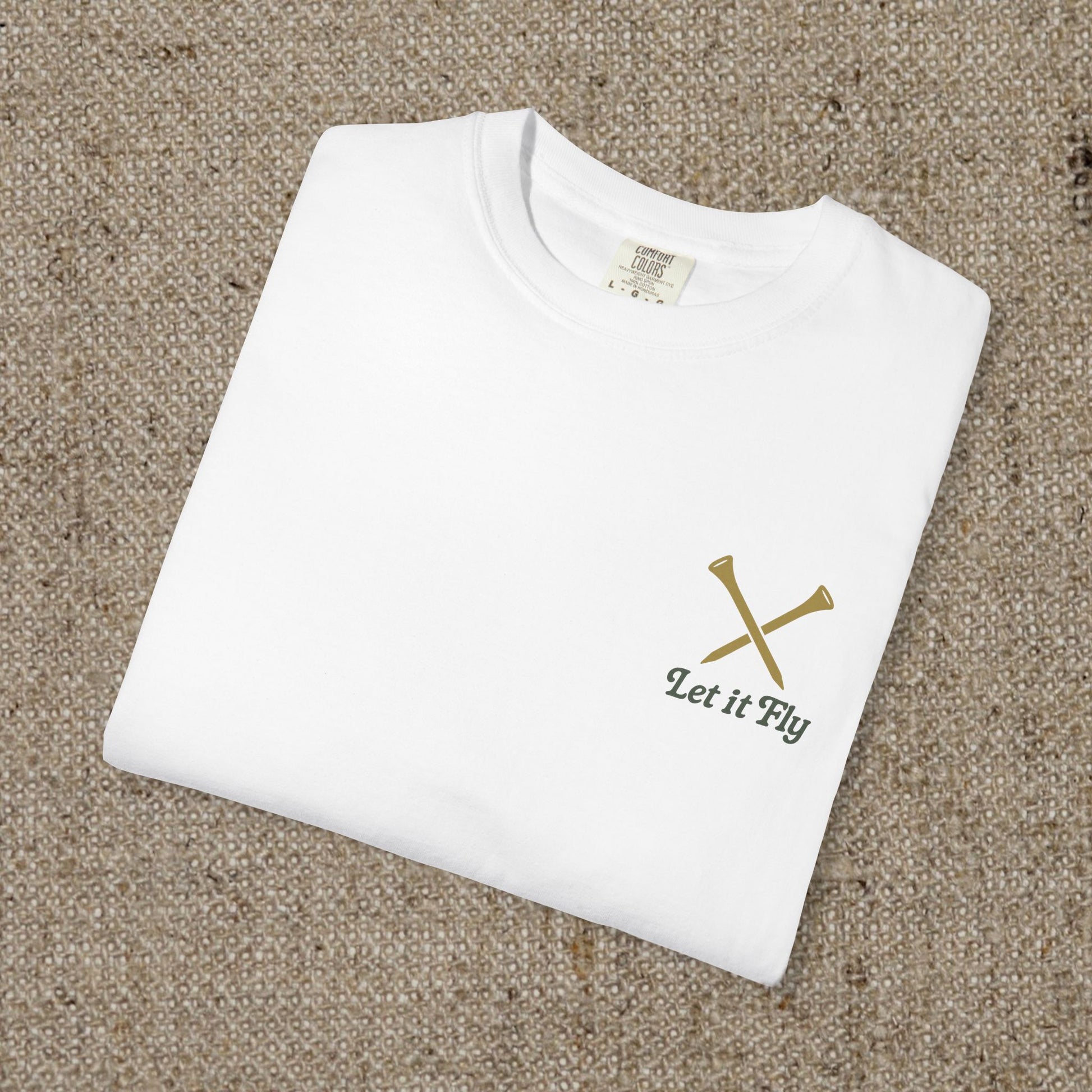 Folded white Tee It High Let It Fly Graphic Tee with 'Let It Fly' text and crossed golf clubs on the chest, highlighting its casual and stylish design.