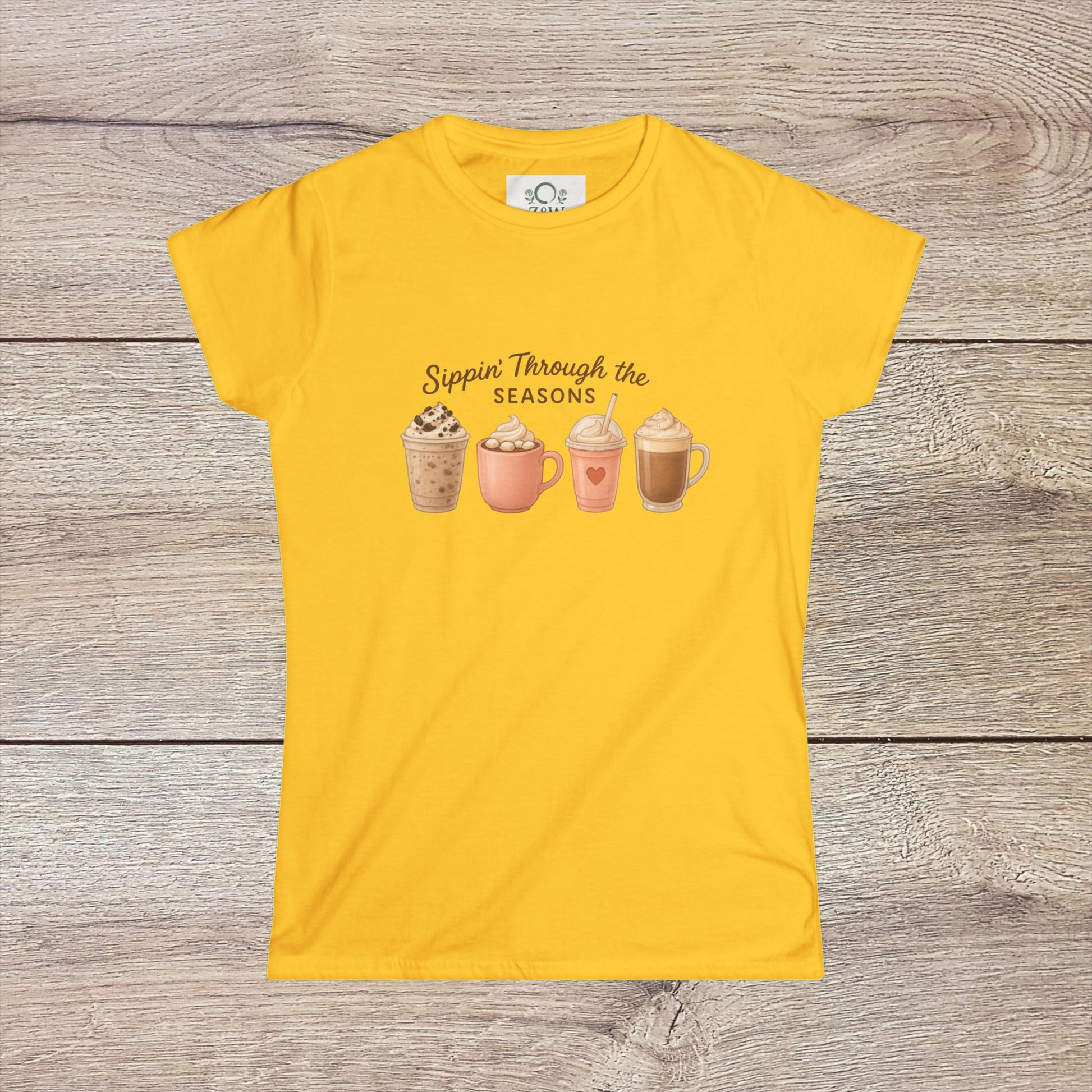 Sippin' Through The Seasons Slim Fit Tee in vibrant yellow, showcasing an illustration of seasonal drinks on a light fabric, crafted from 100% combed cotton.