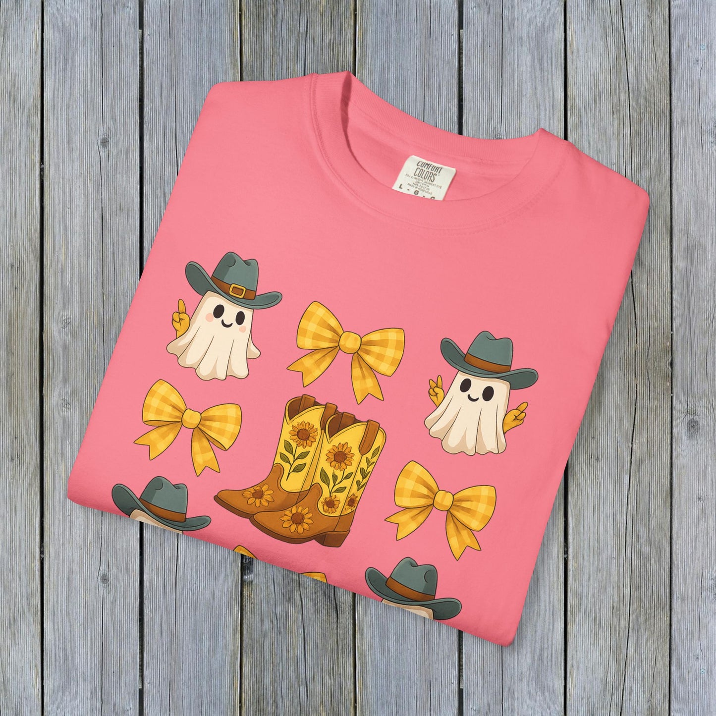Cute Halloween T-Shirt displayed flat, highlighting a vibrant design with ghosts, cowboy boots, and bows on a bright background, ideal for unisex fall fashion, made with eco-friendly fabric.