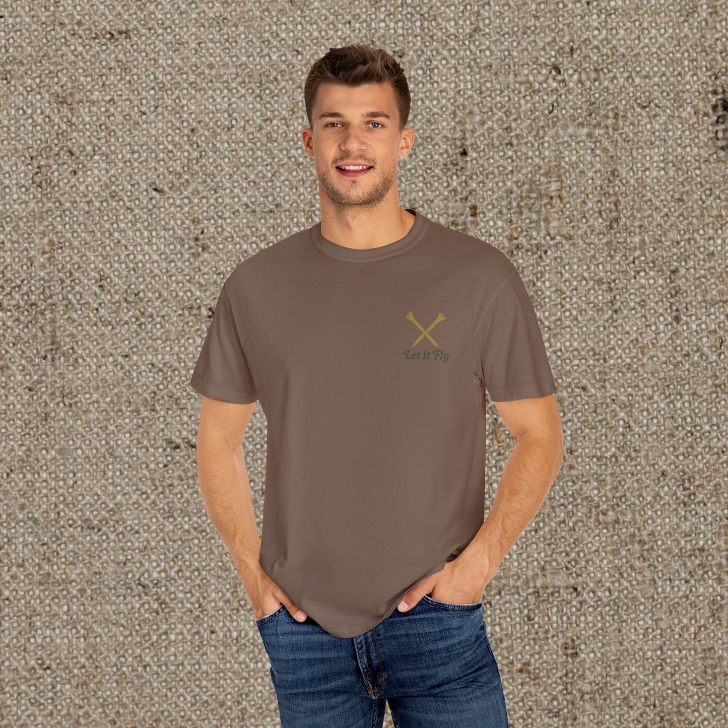 Model wearing a brown Tee It High Let It Fly Graphic Tee, showcasing crossed golf clubs on the chest. A perfect blend of comfort and style.