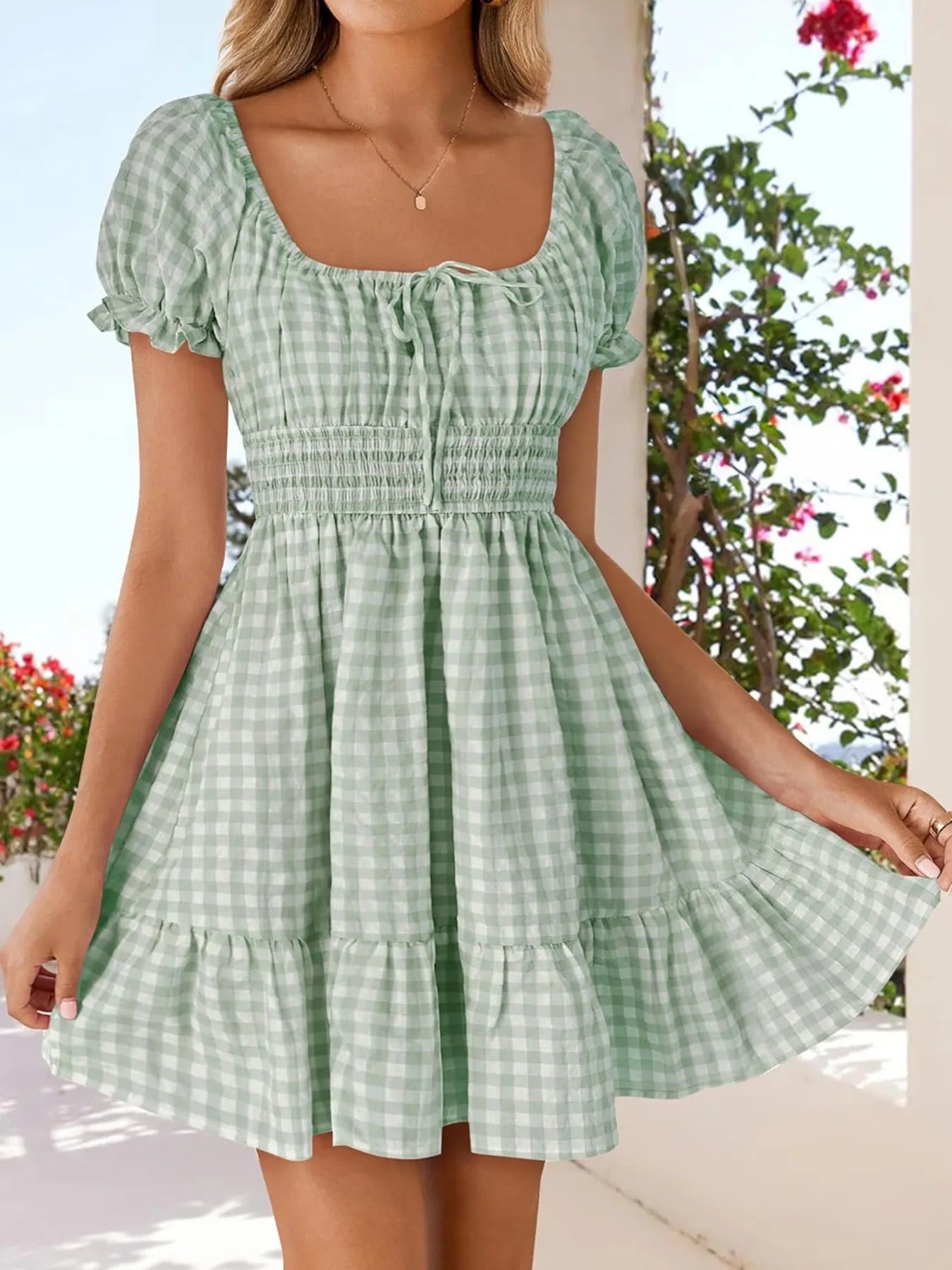 Women’s Gingham Puff Sleeve Smocked Dress in green, styled against a beautiful outdoor setting, showcasing its lightweight and breathable fabric.