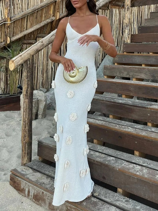 Elegant backless flower print maxi sweater cami dress showcased on a model standing on wooden steps, perfect for a stylish beach outing. Slightly stretchy 100% polyester material.