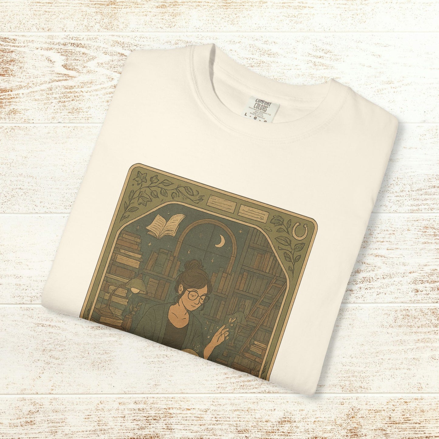 Page Turner Tarot Tee in cream, featuring a mystical design of a woman engaging with books, ensuring comfort and sustainability with eco-friendly cotton.