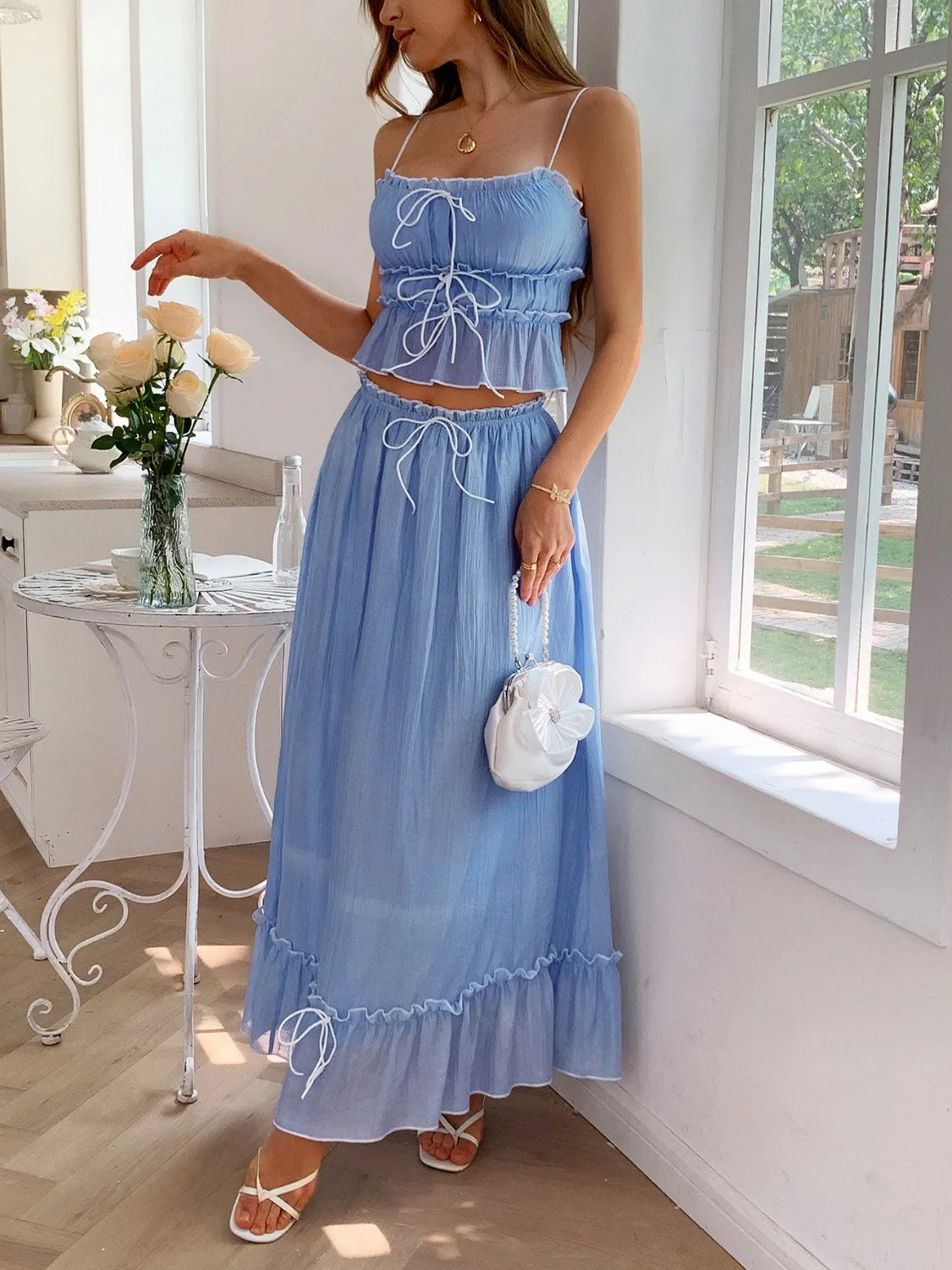 Model wearing a Two-Piece Frill Square Neck Cami and Ruched Skirt Set in Stretchy Lyocell Blend, featuring a light blue color and styled with flowers in hand.