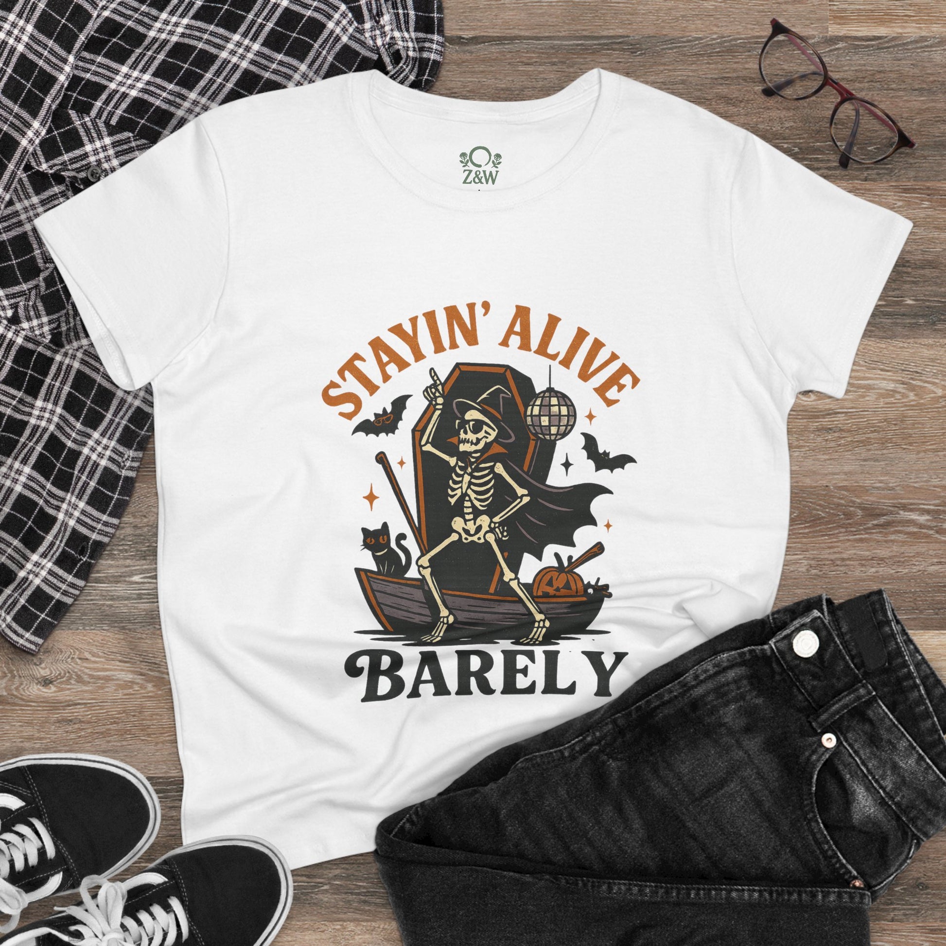 Flat lay of the Stayin’ Alive T-Shirt styled with black jeans and glasses, showcasing a fun Halloween unisex tee.