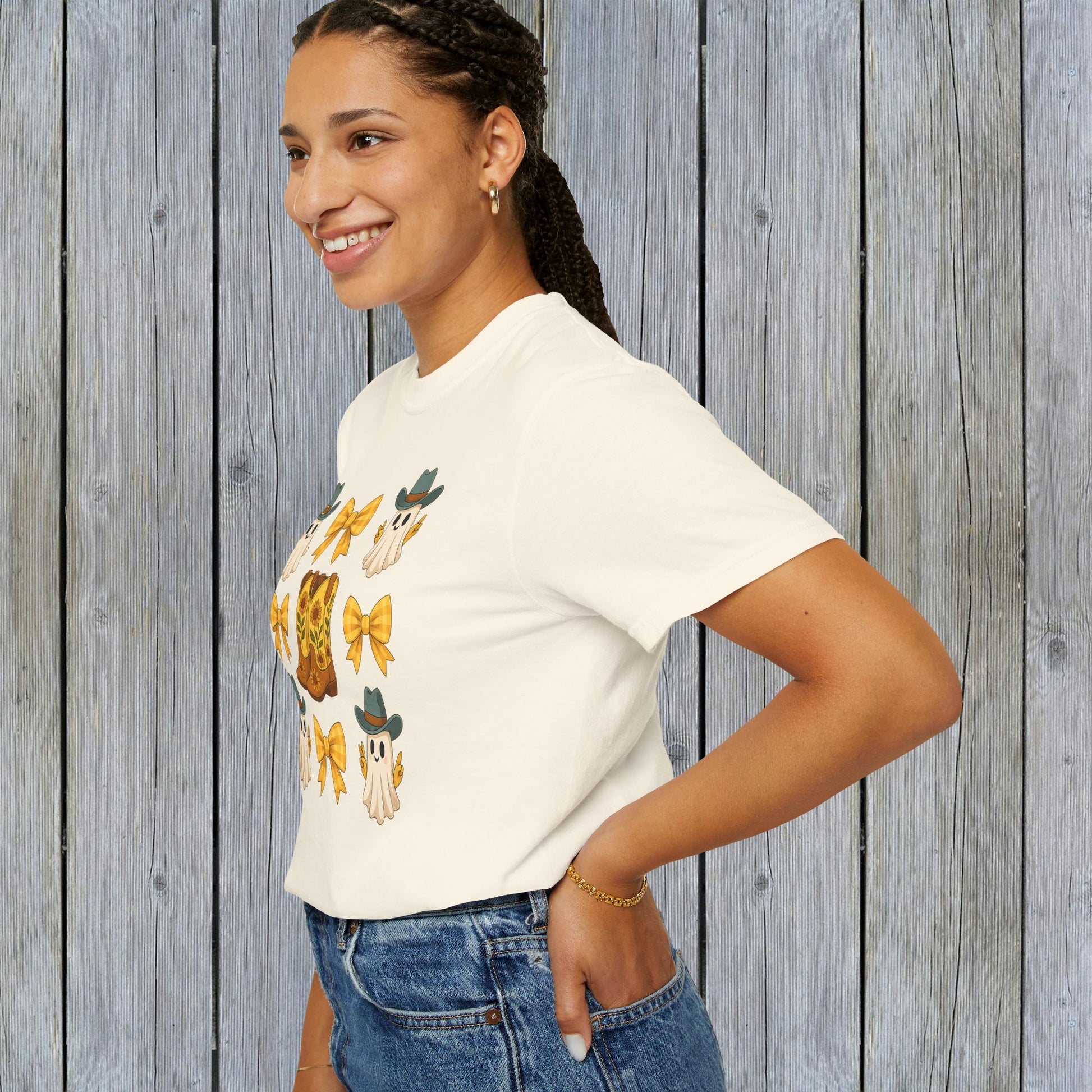 Side view of a model wearing a Cute Halloween T-Shirt with a whimsical ghosts and cowboy boots graphic, ideal for unisex fall fashion, crafted in eco-friendly material.