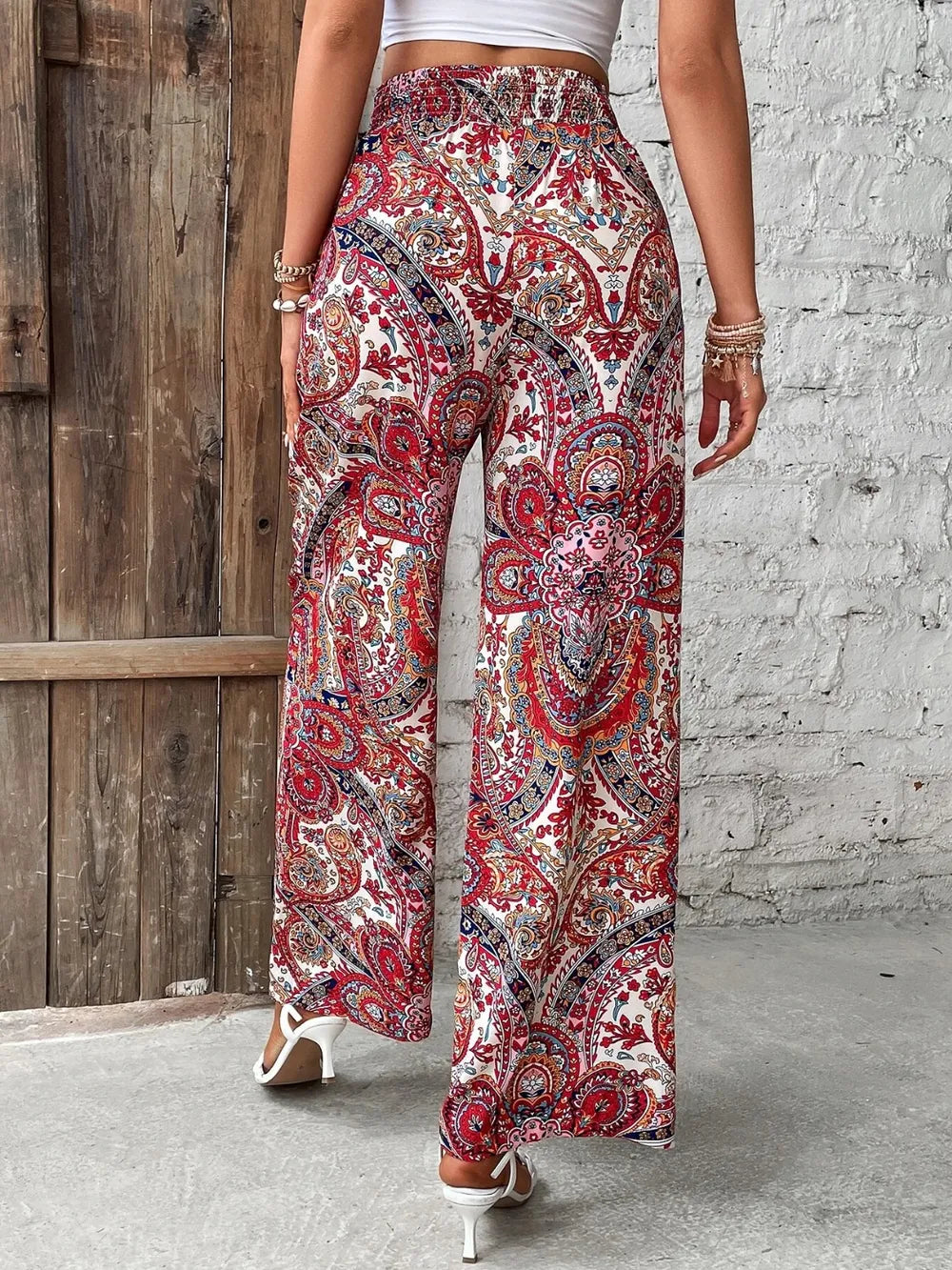Back view of the Trendy Printed Wide Leg Pants with Tied Detail in red paisley design, emphasizing the elastic waistband and flowy silhouette, made from 100% opaque polyester for all occasions.
